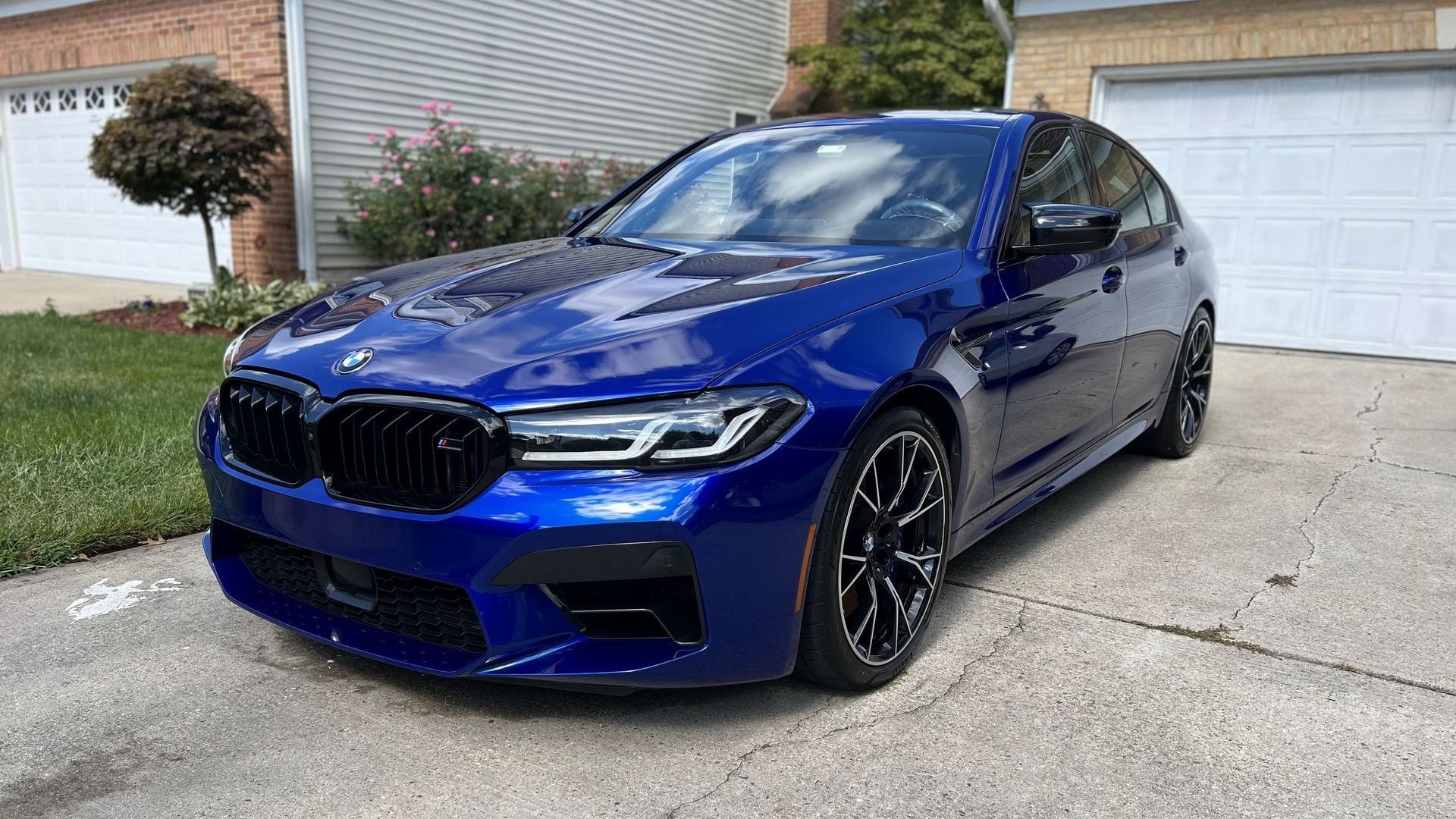 a blue bmw m5 is parked in front of a garage .