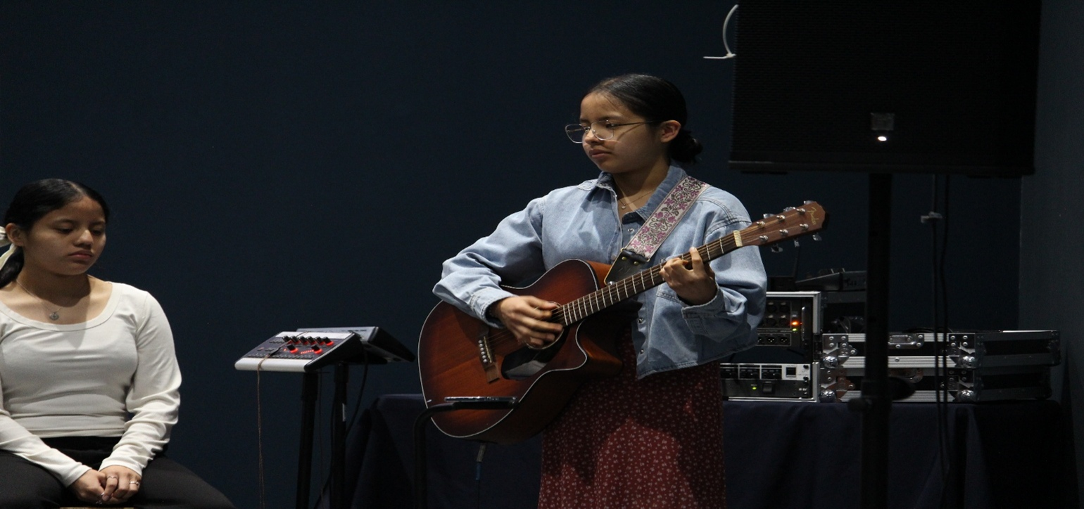 A person is holding a card with a cross on it in front of a laptop.