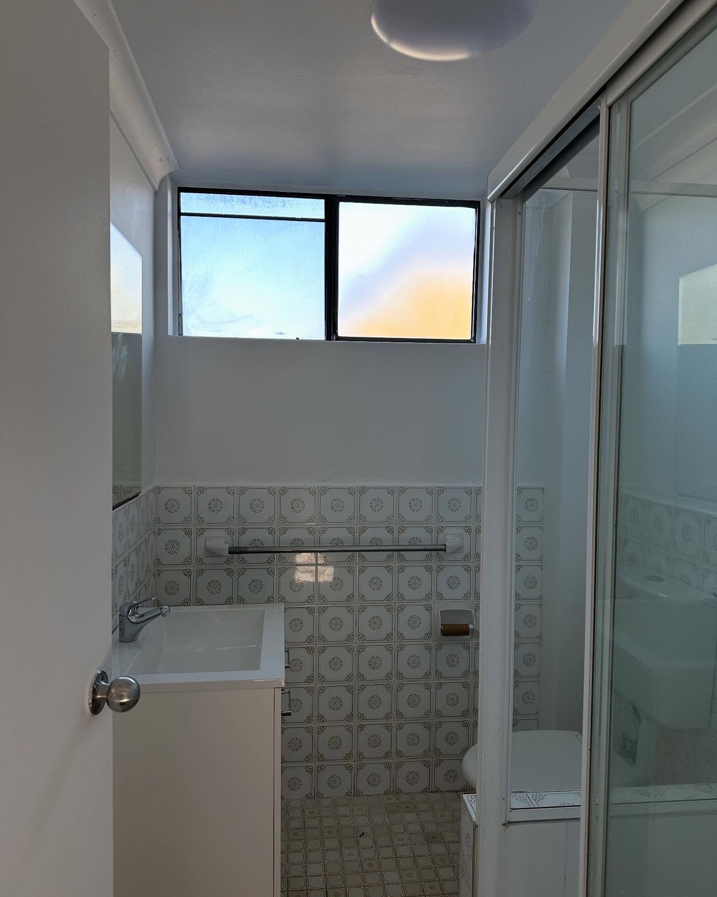 Small bathroom with a window, sink, shower, and toilet. White and blue color scheme — CPAINT in Forster, NSW