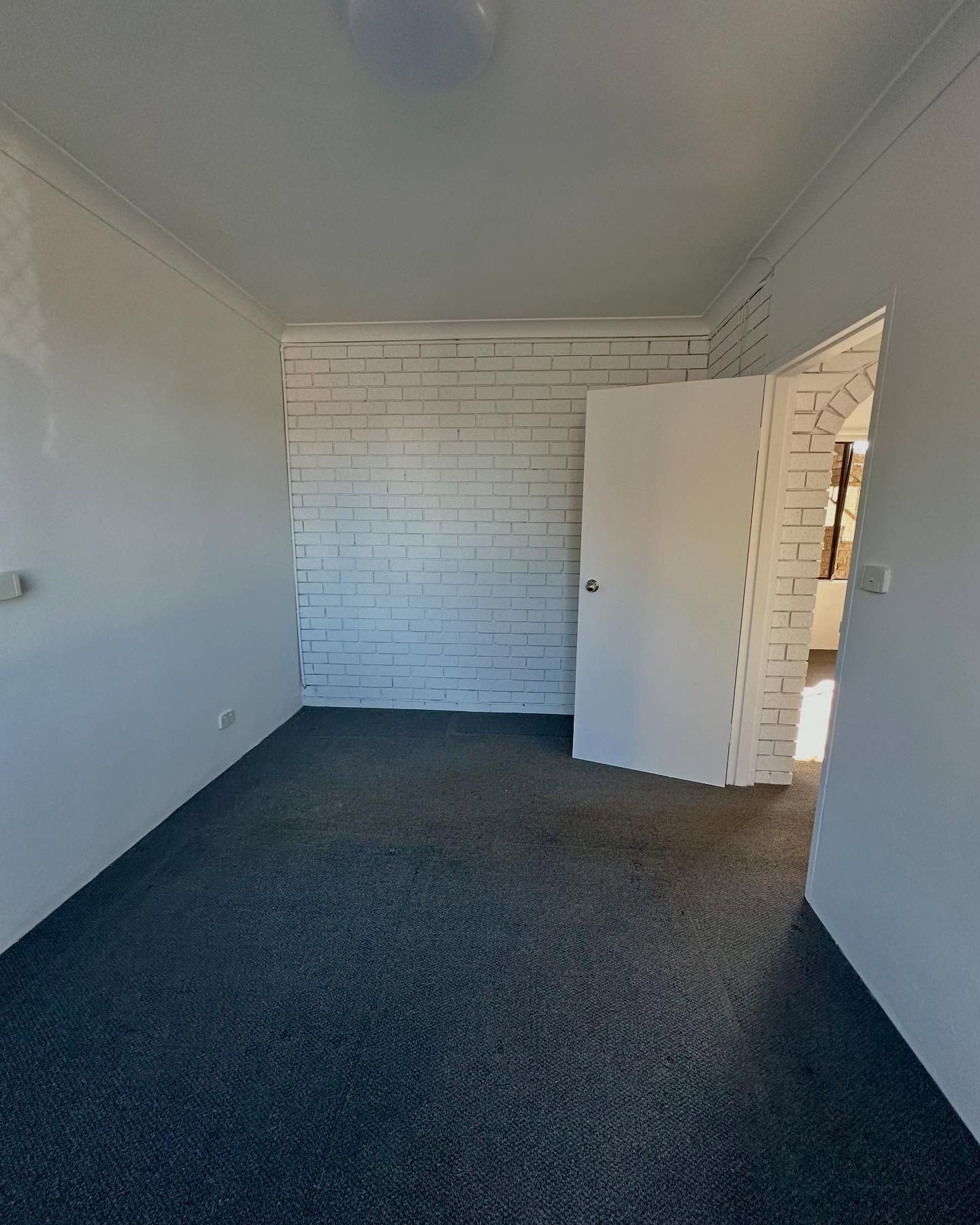 Empty Room With Dark Carpet and White Brick Accent Wall — CPAINT in Forster, NSW