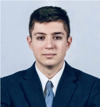 A young man in a suit and tie looks at the camera