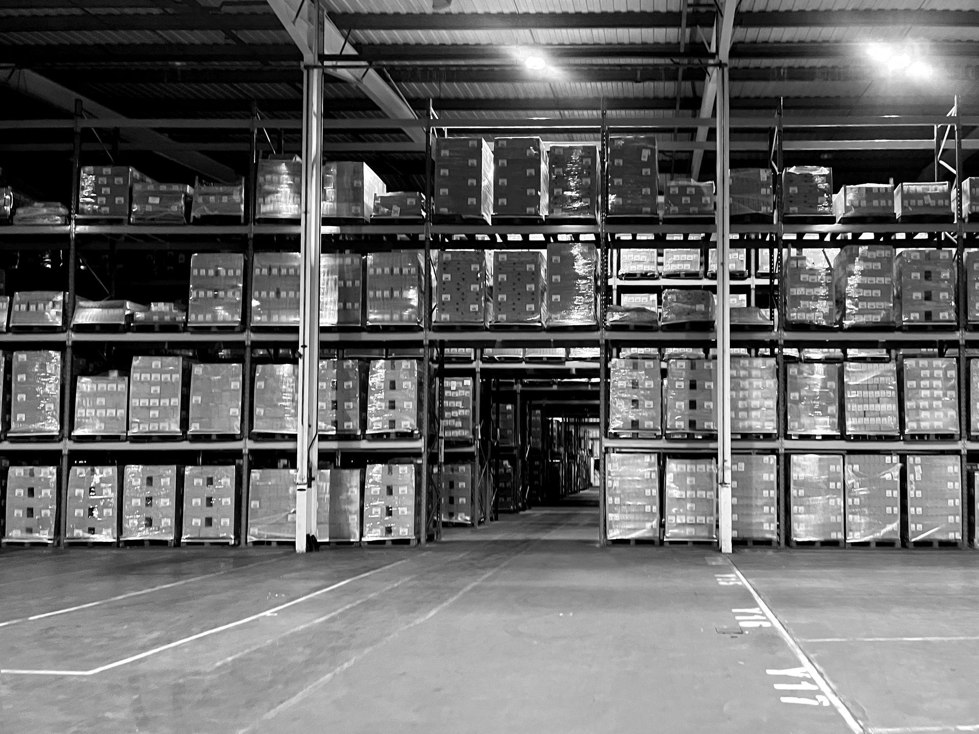 A black and white photo of a large NSK Fulfilment warehouse filled with lots of boxes.