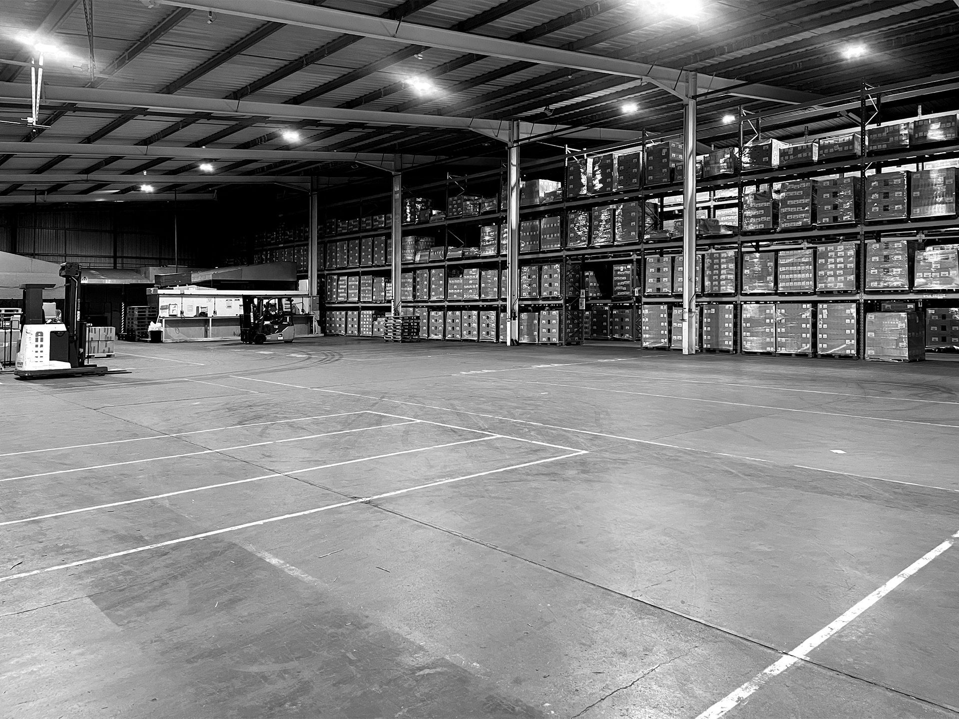 A black and white photo of a large NSK Fulfilment warehouse filled with lots of boxes.