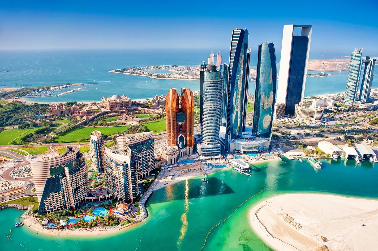 Abu Dhabi cityscape with skyscrapers, turquoise water, and a coastal landscape.