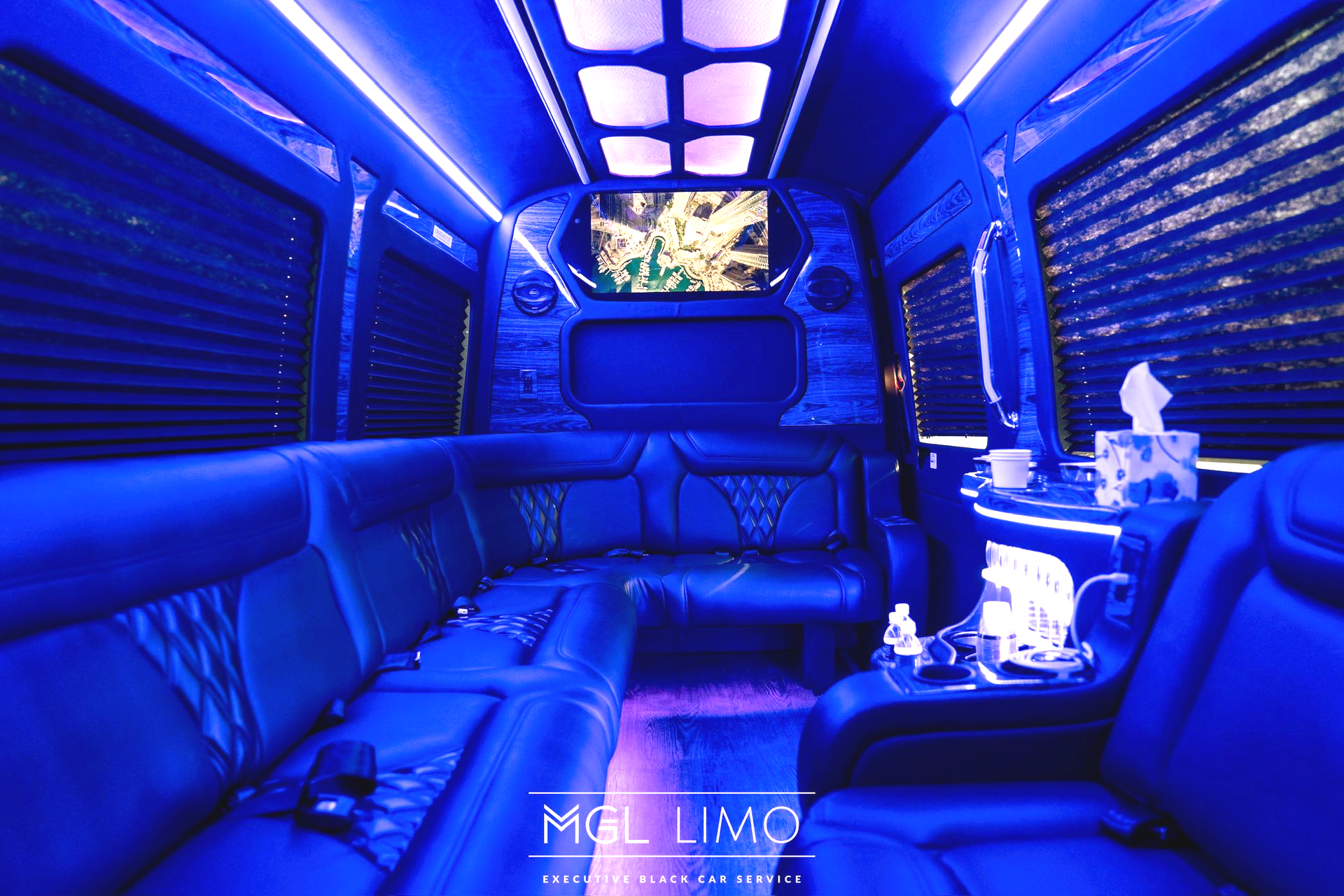 Luxurious van interior with cream leather seats, multiple screens, and black window shades.