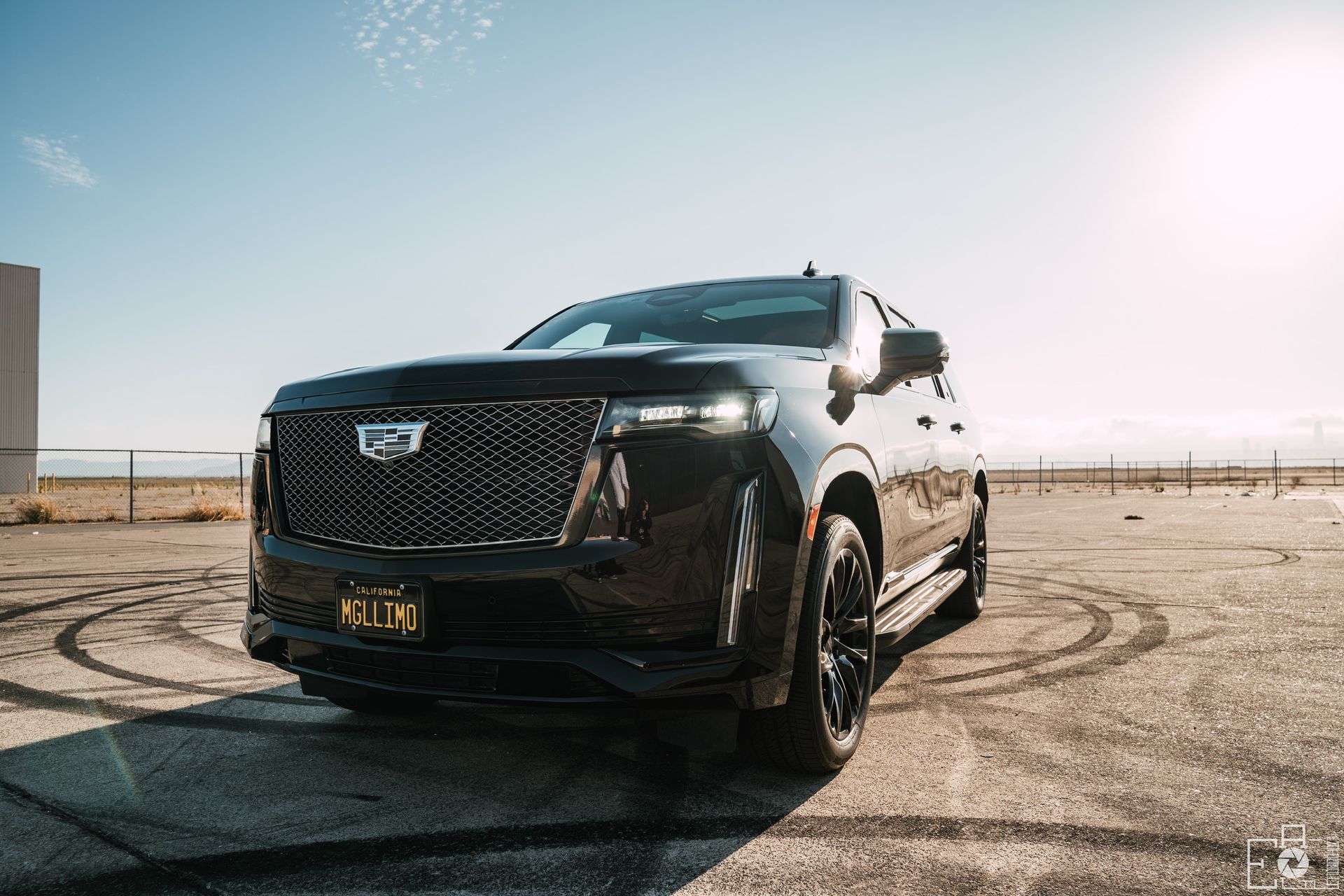 Black Cadillac Escalade parked on a city street, buildings in background.