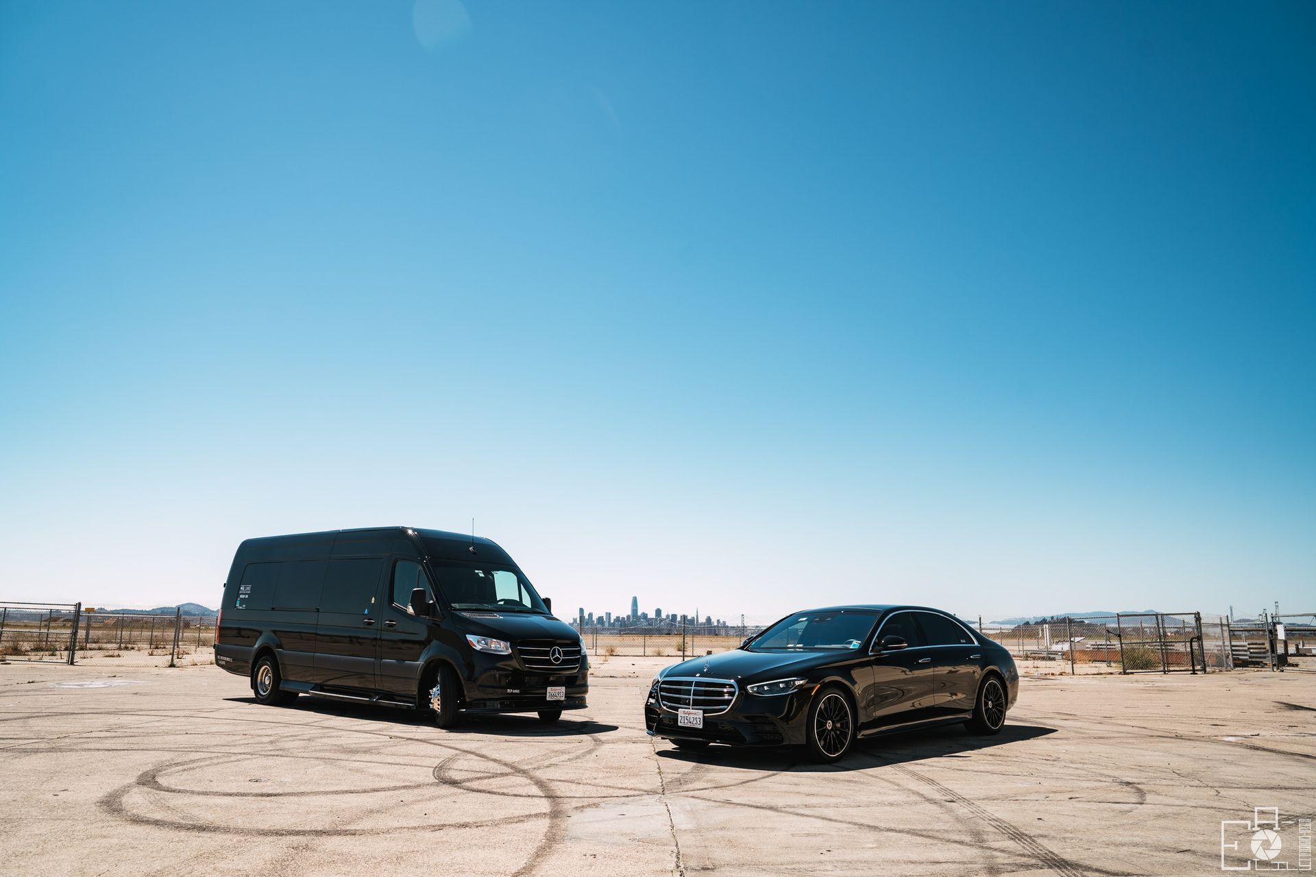 Dark gray Cadillac sedan parked on a city street at dusk, lights reflecting on the car.