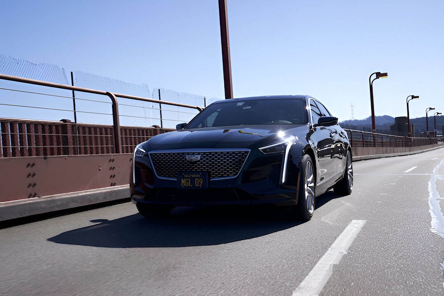 Black Mercedes-Benz sedan parked on a street lined with trees, sunlight in the background.