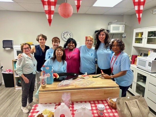 a group of women posing behind a setup for an indoor picnic