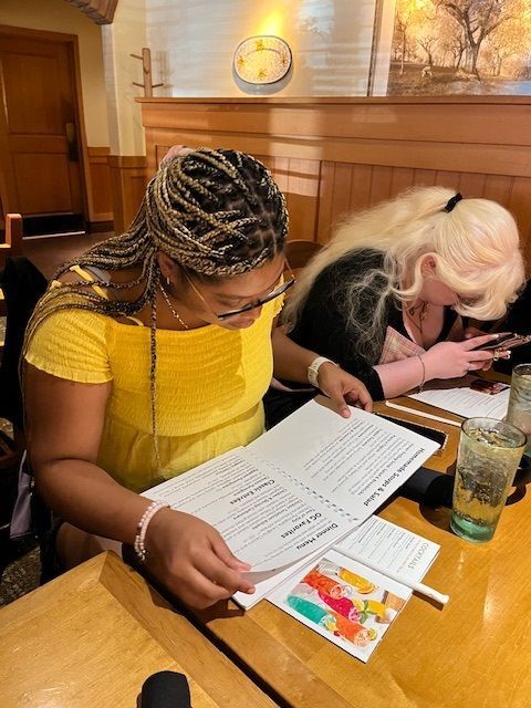 a woman reading a large print menu at a restaurant