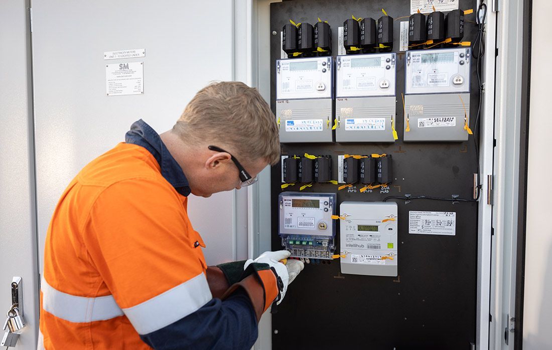 A Man in an Orange Safety Vest is Working on a Electrical Box — Macquarie Electric in Dubbo, NSW