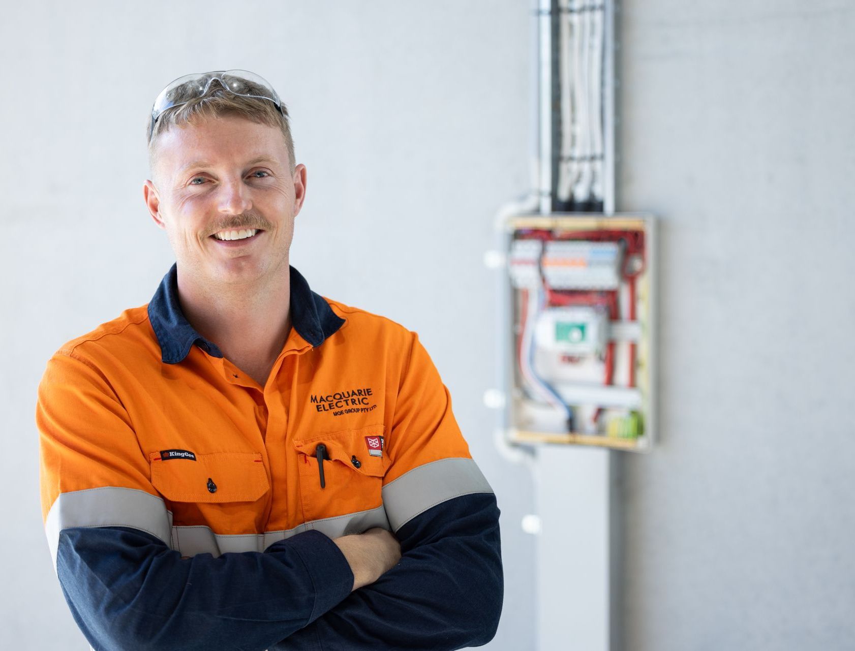 A smiling male electrician wearing a high-visibility orange and navy work shirt -Macquarie Electric in Dubbo, NSW