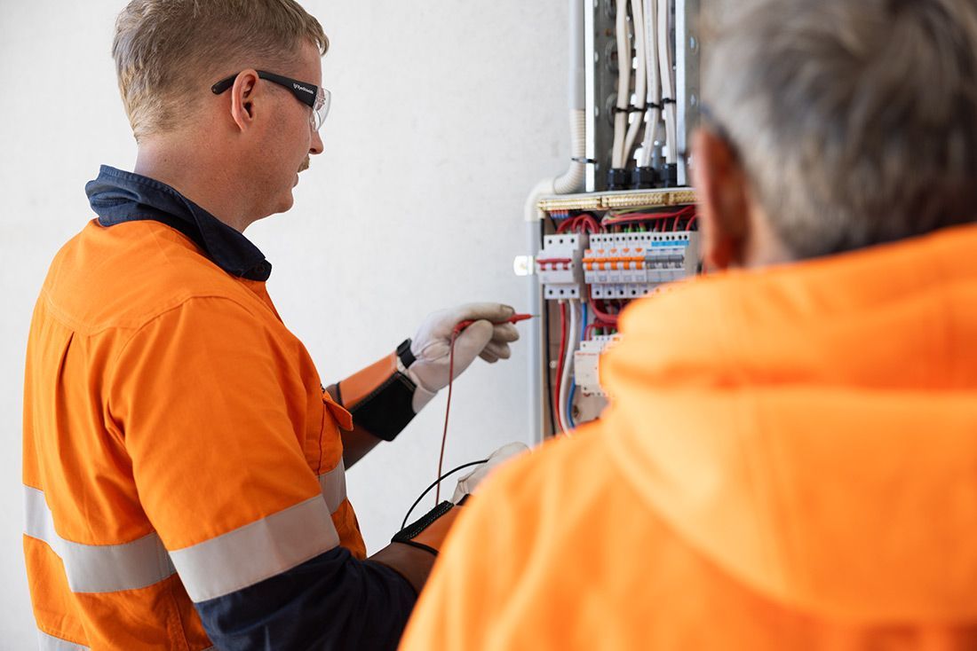 A Man in an Orange Jacket is Working on an Electrical Box — Macquarie Electric in Forbes, NSW