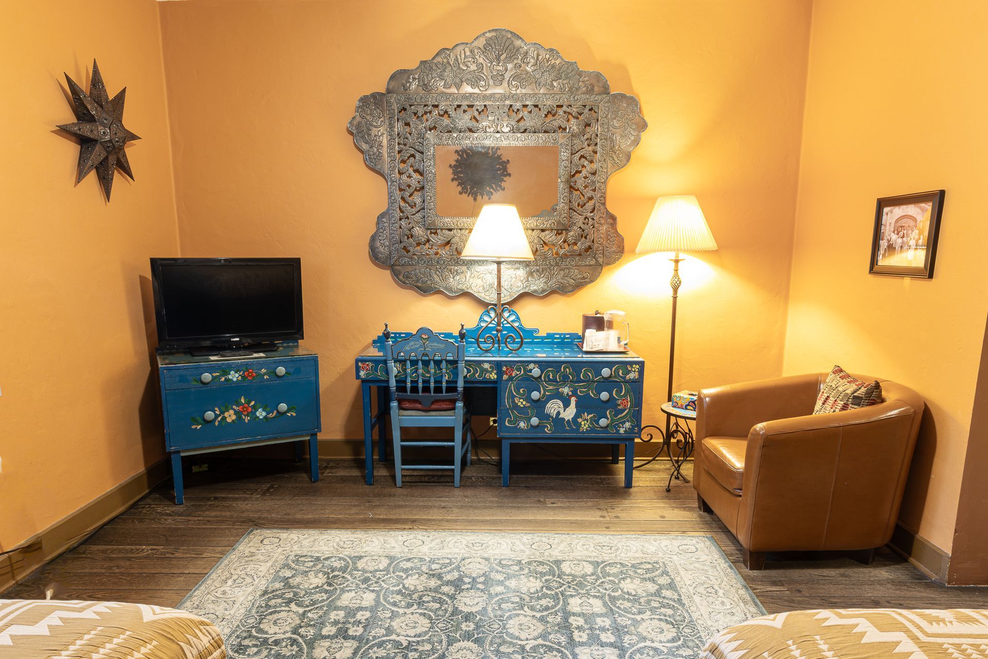 Room with orange walls, ornate blue furniture, large mirror, and leather armchair.