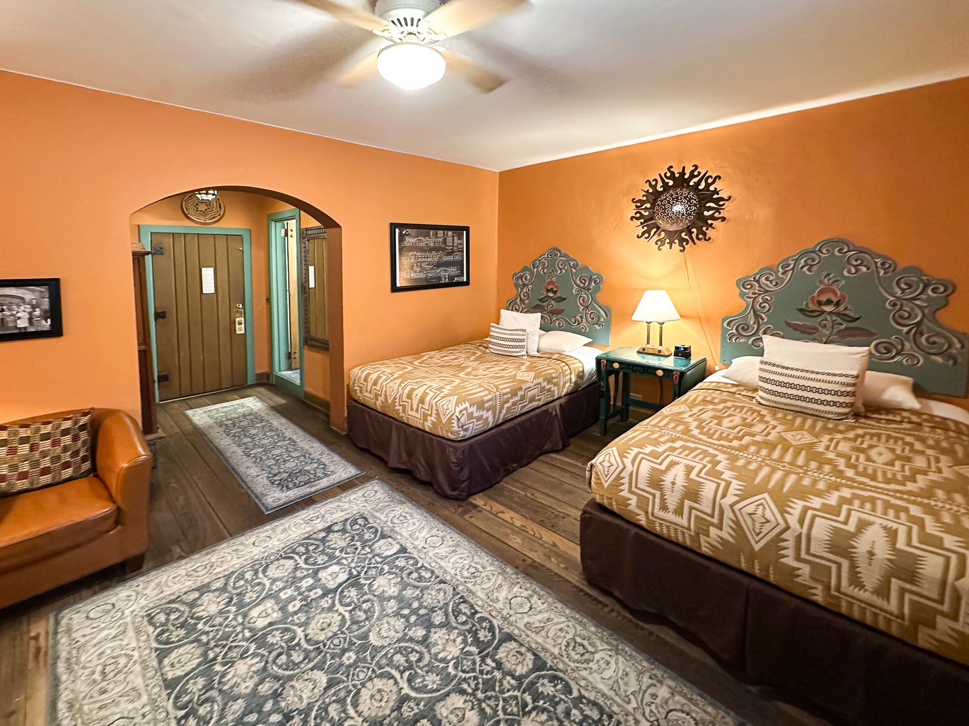 Hotel room with orange walls, two twin beds, and a leather armchair.