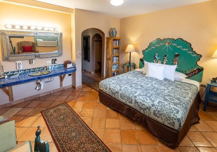 Bedroom with teal bed headboard and vanity, terracotta tile floor, and doorway.