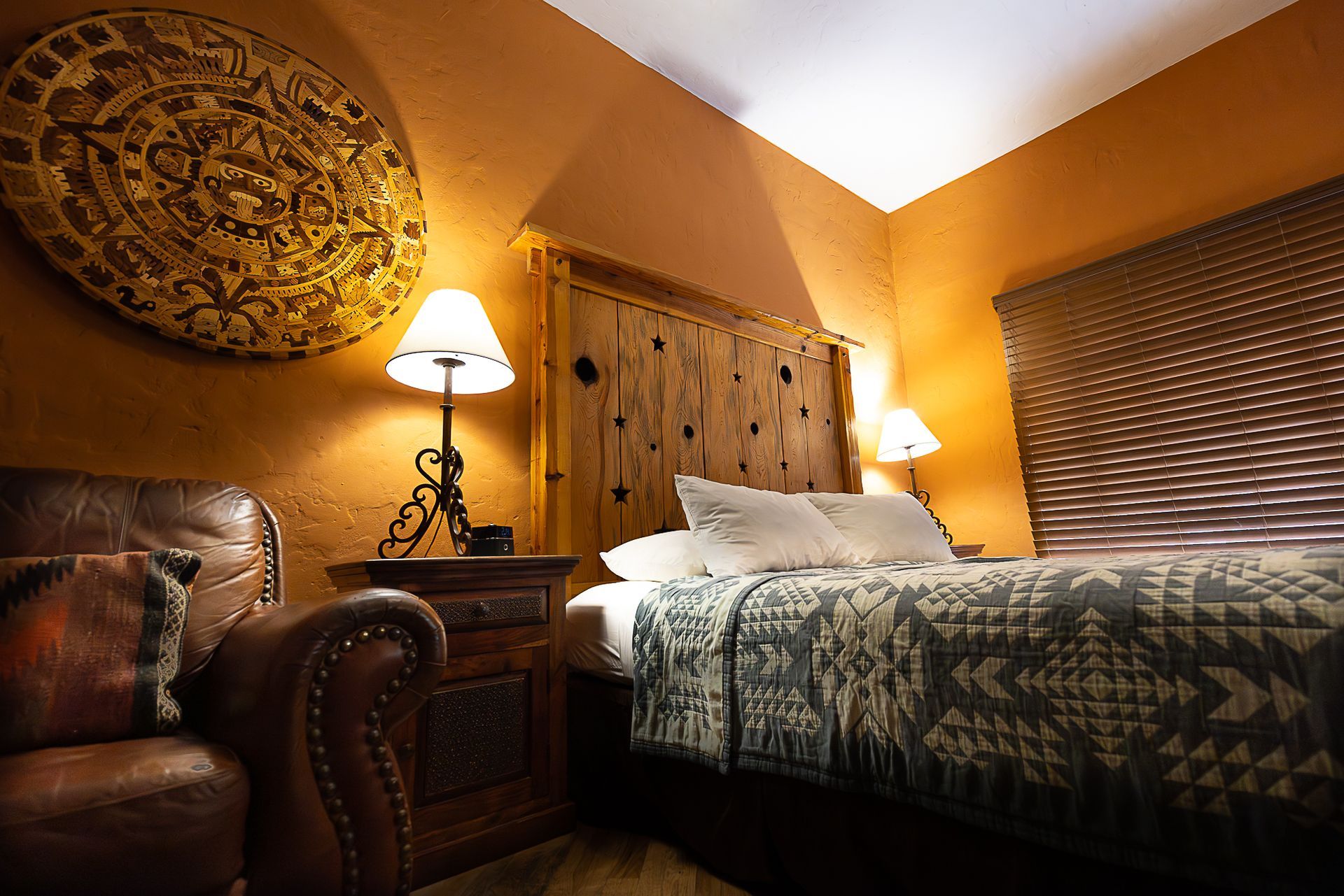 Cozy bedroom with a bed, leather chair, lamp, and a wall decoration. Earth tones create a warm ambiance.