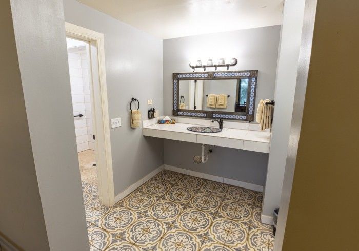 Bathroom with patterned floor, floating vanity, large mirror, and open doorway.