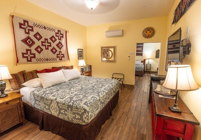 Bedroom with southwestern decor, including a woven wall hanging, wood furniture, and a view into another room.