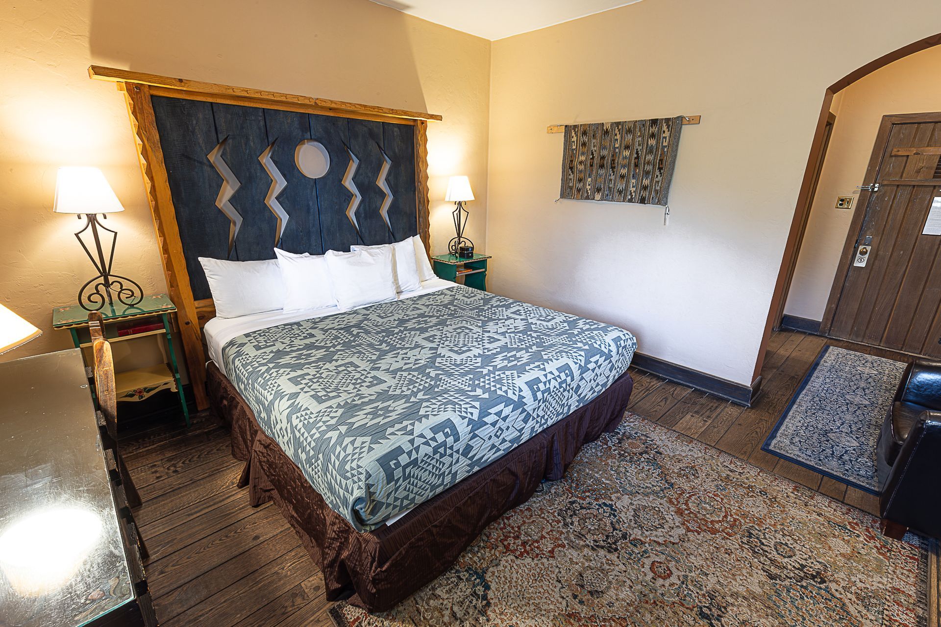 Hotel bedroom with a bed, rug, nightstand, and an entryway.
