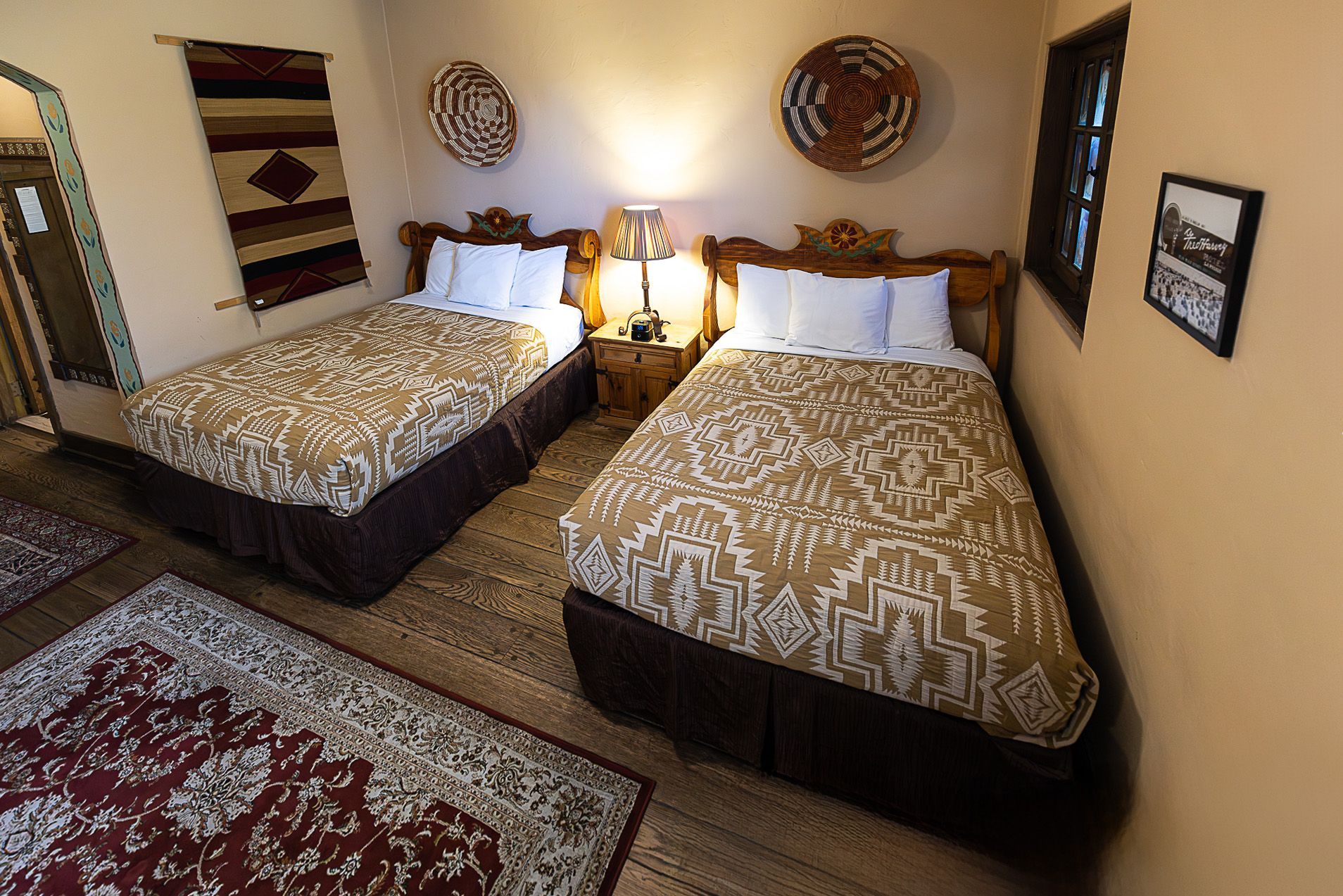 Two beds in a Southwestern-style room; tan and brown patterned bedding, rugs, and wall decor.