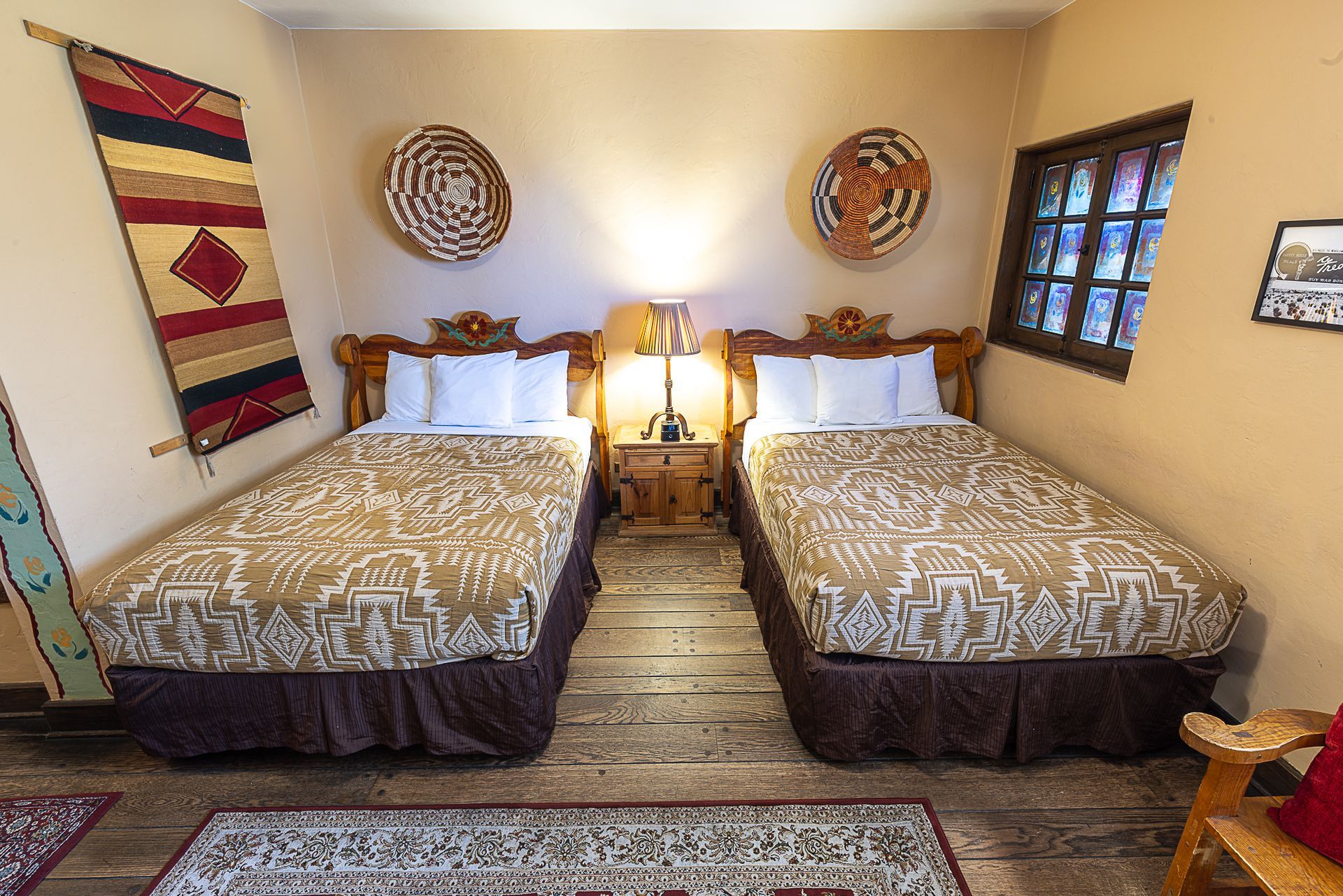 Twin beds in a southwestern style room with woven baskets, rug, and tapestry.