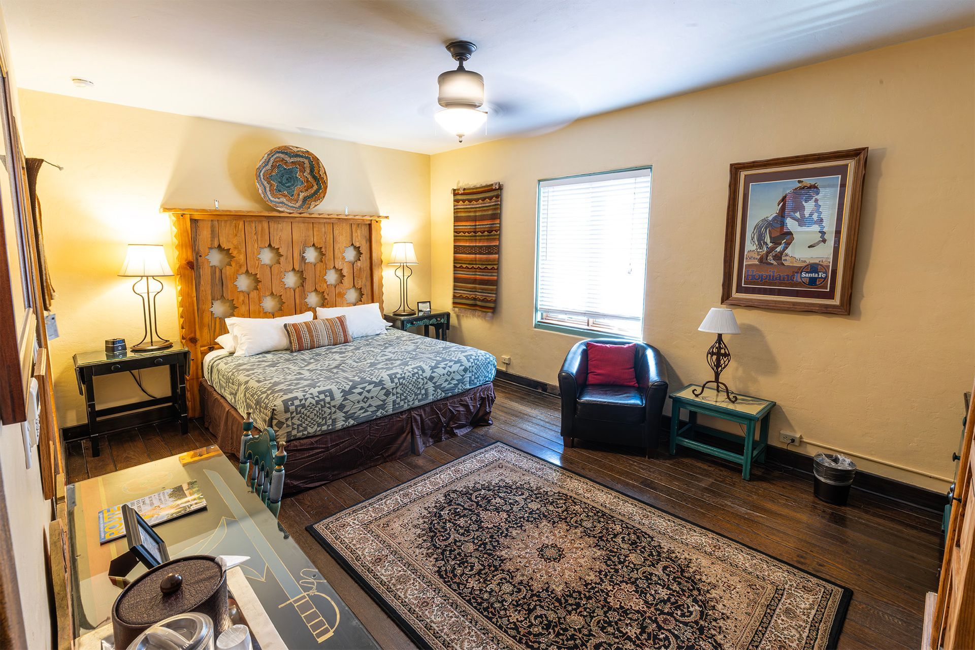 Bedroom with a wooden headboard, rug, painting, and armchair.