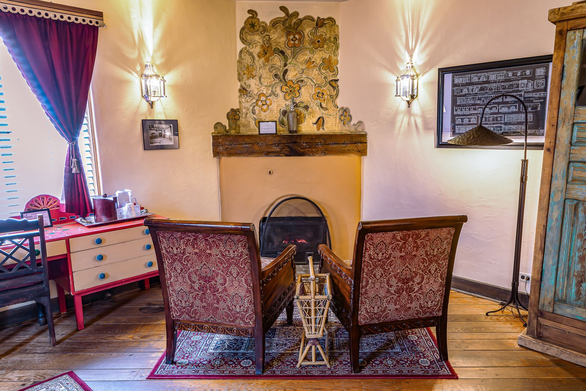 Cozy room with a fireplace, two patterned armchairs, and antique furnishings.