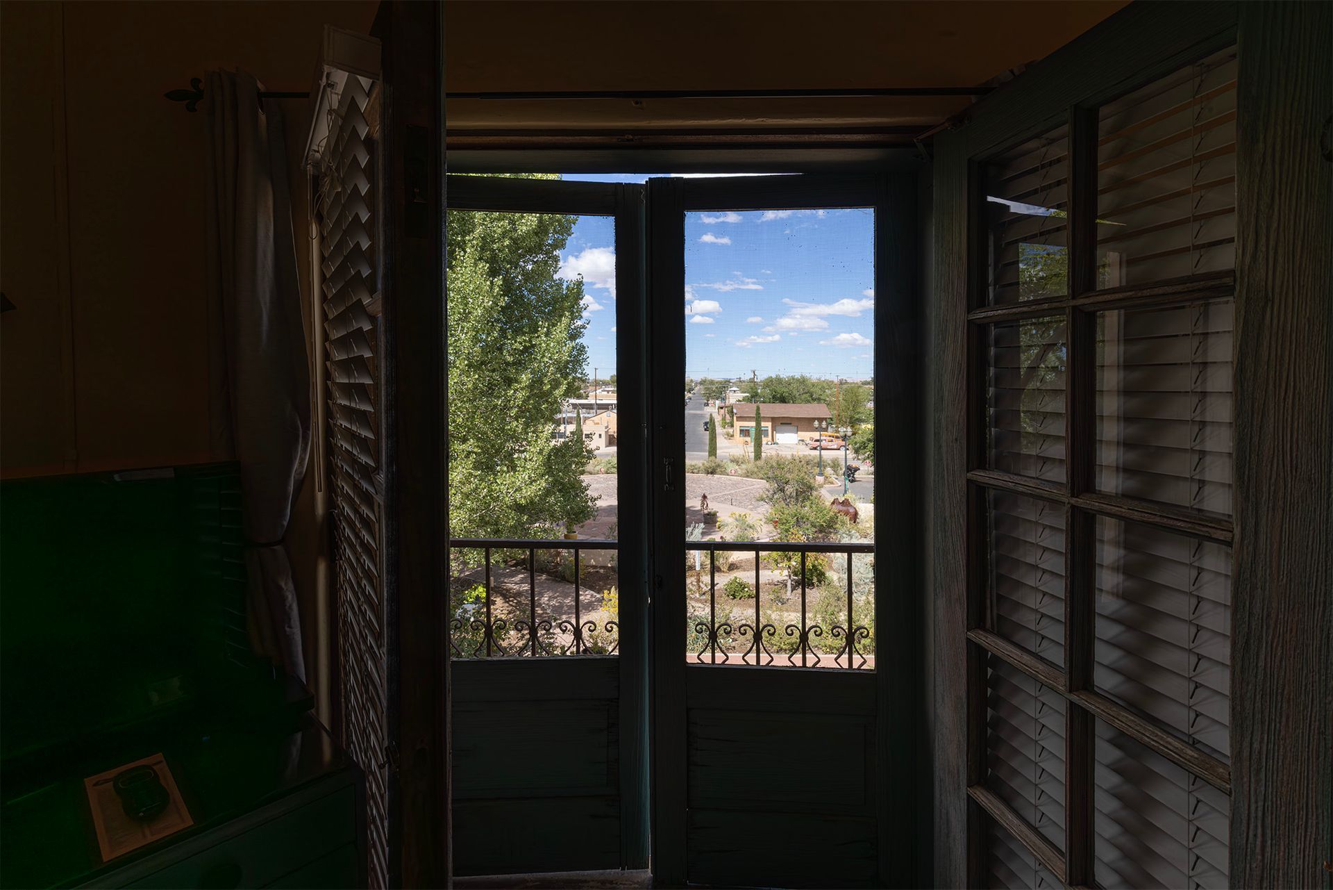 A view through green balcony doors overlooking a sunny outdoor scene.