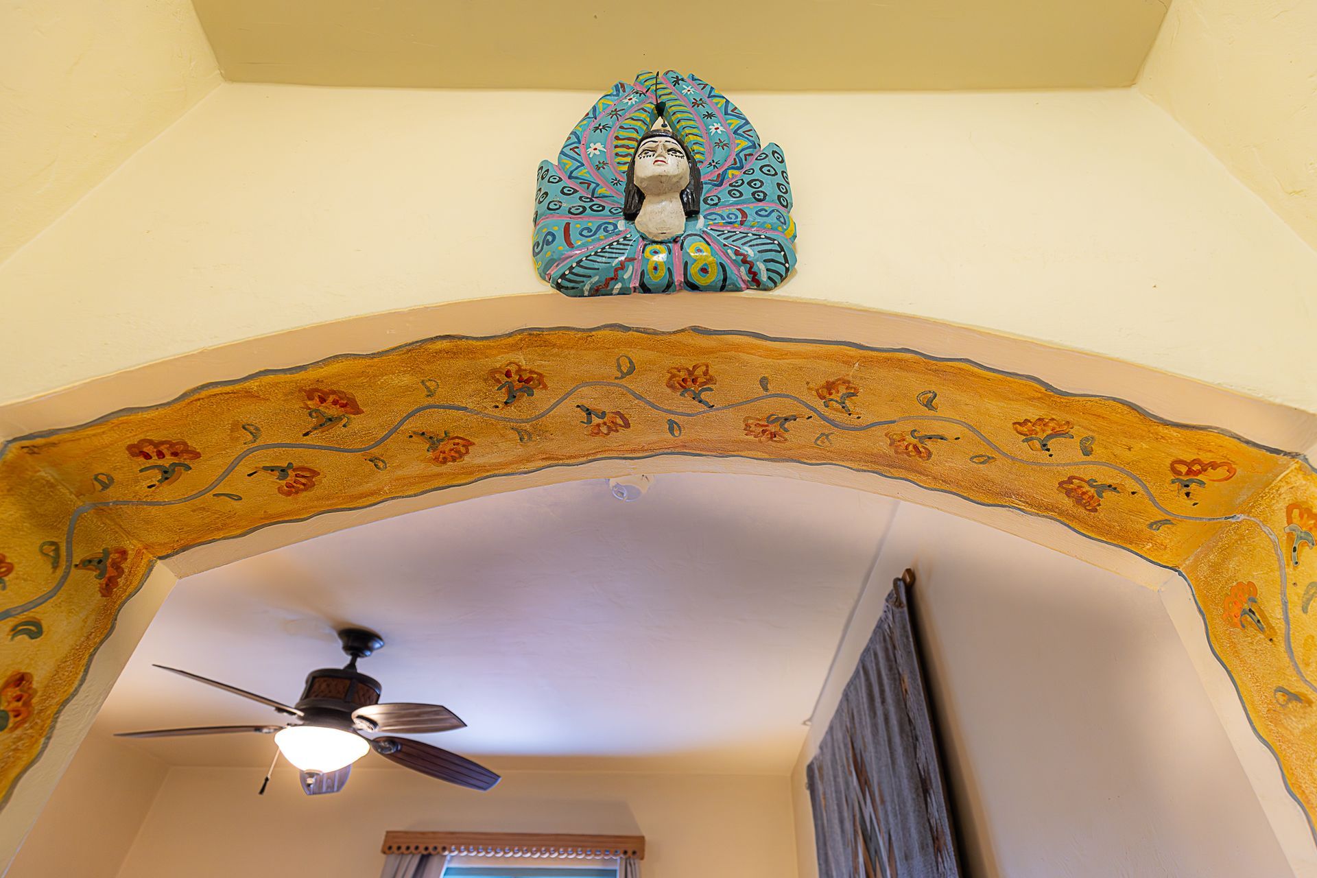 Archway with painted floral design, blue decorative head sculpture above.