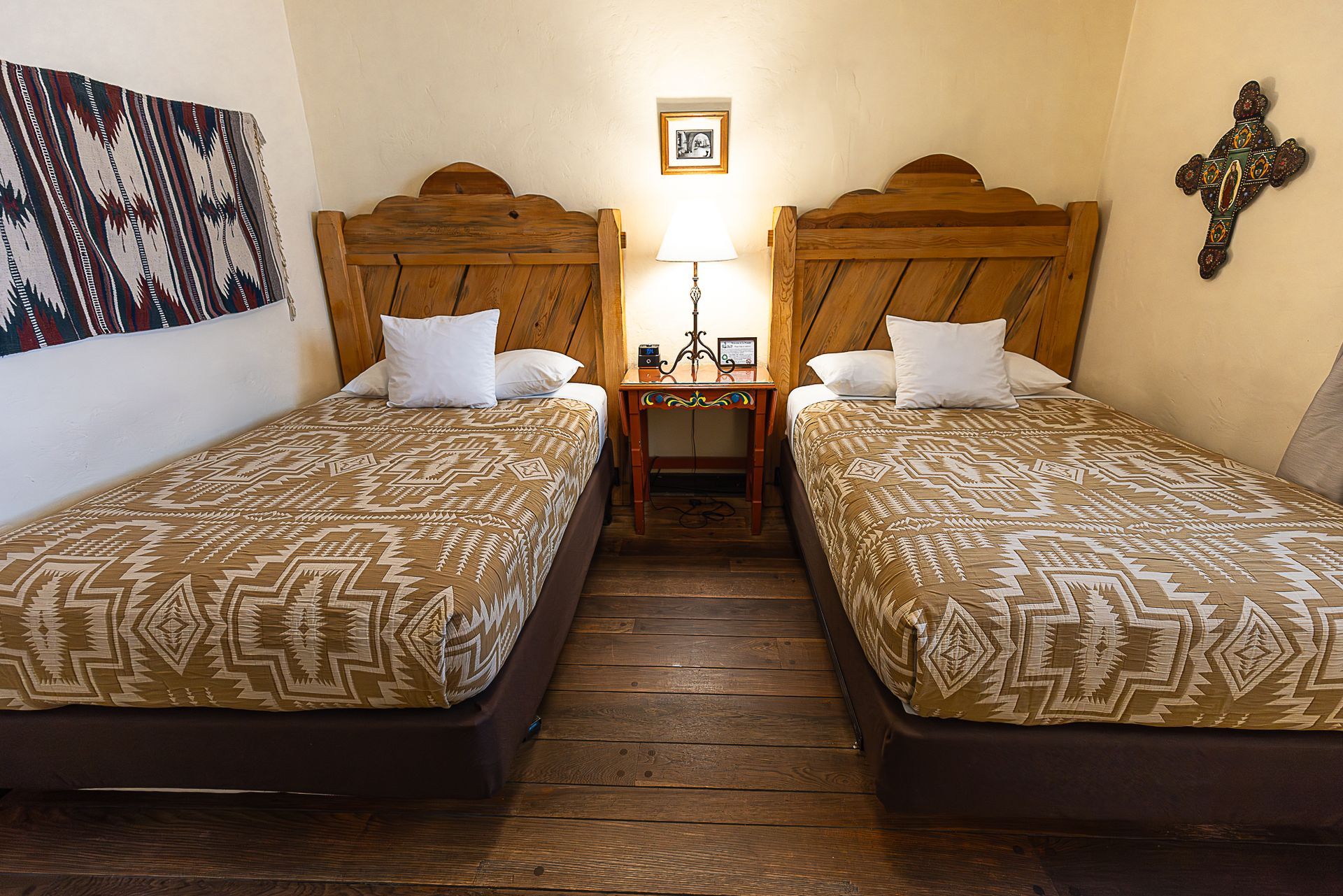 Two twin beds in a room with wooden headboards, a nightstand, and southwestern decor.