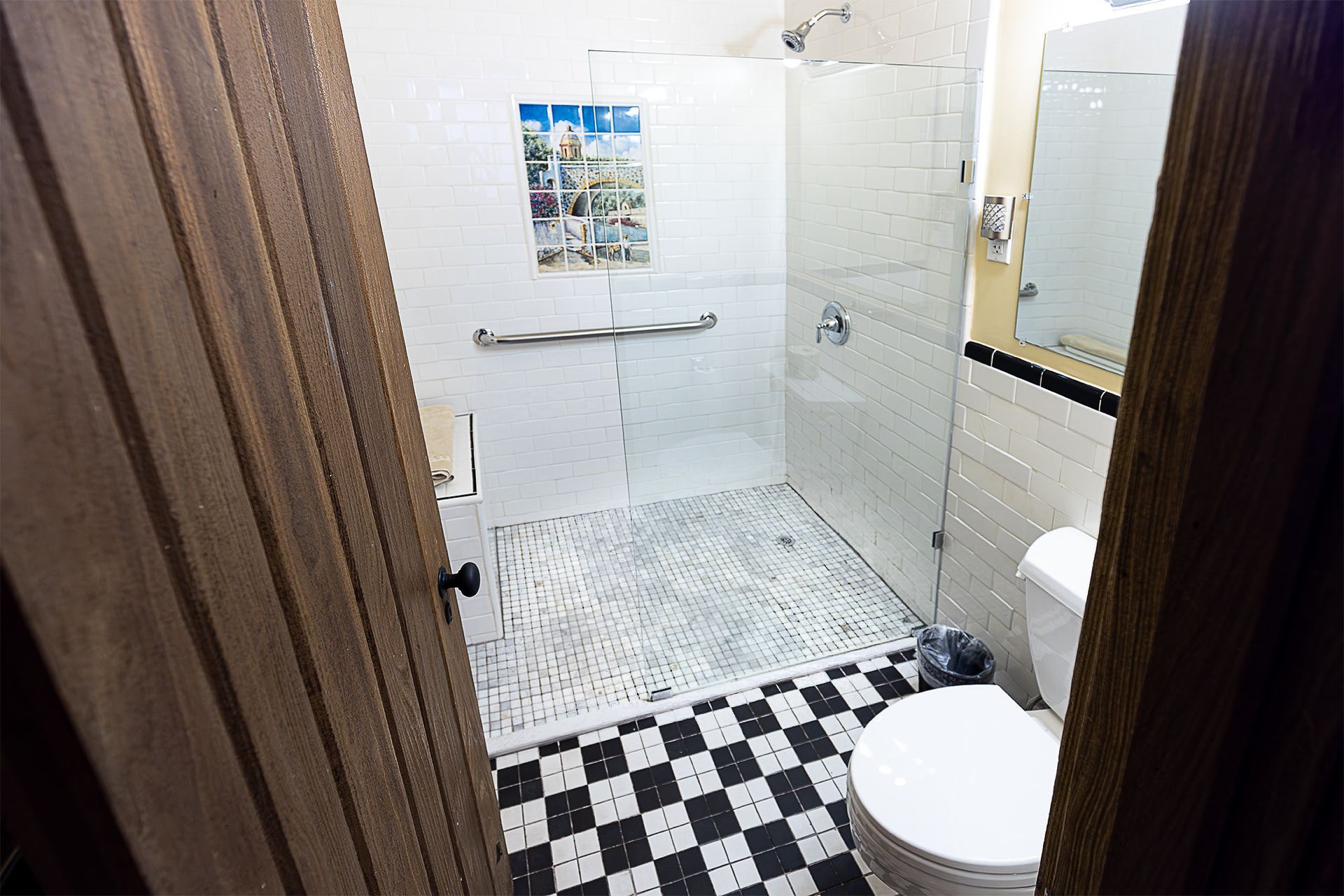 Bathroom with black and white checkered floor, walk-in shower, and toilet.