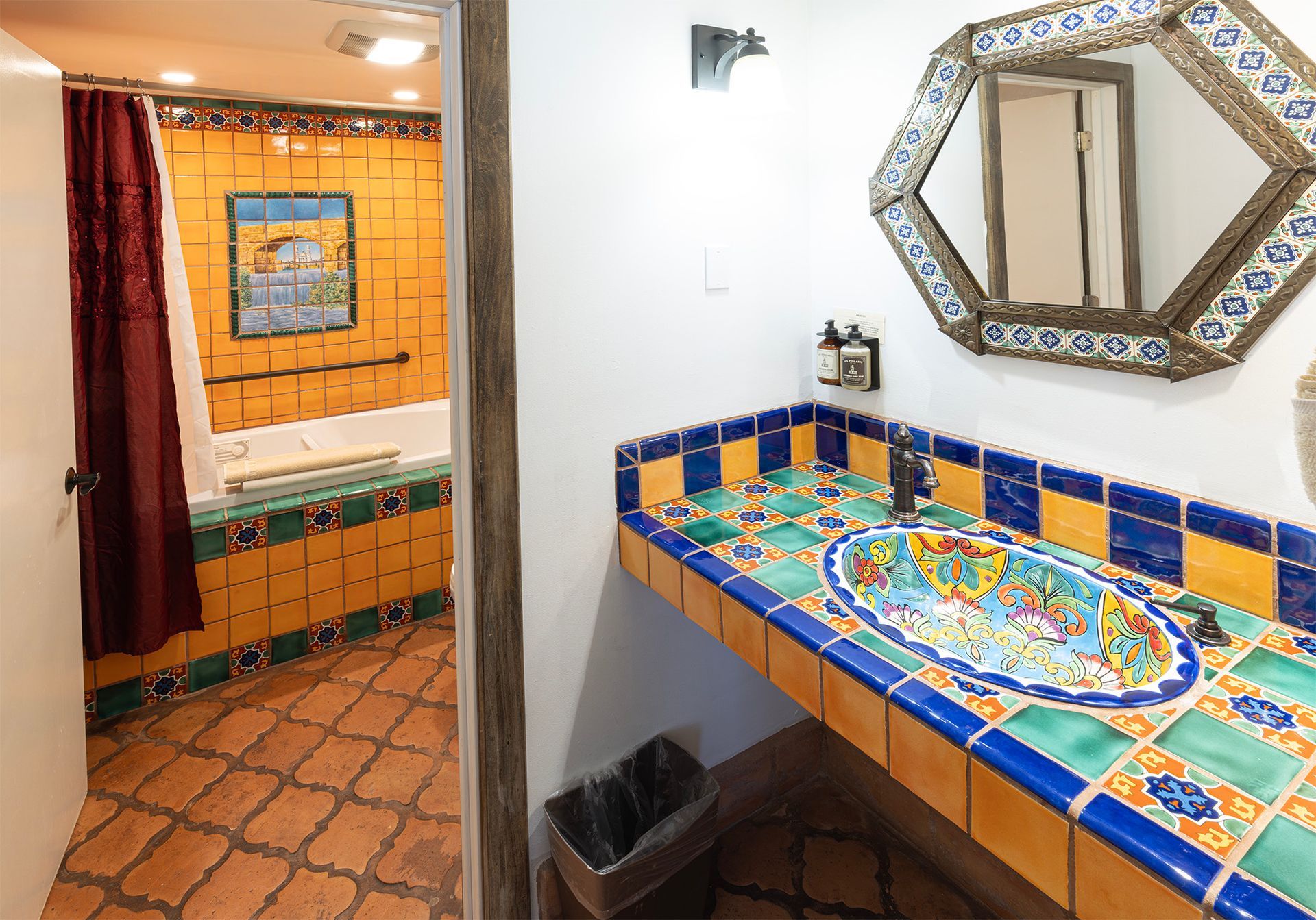 Bathroom with colorful tile, mirror, and sink. Bathtub area visible in the background.