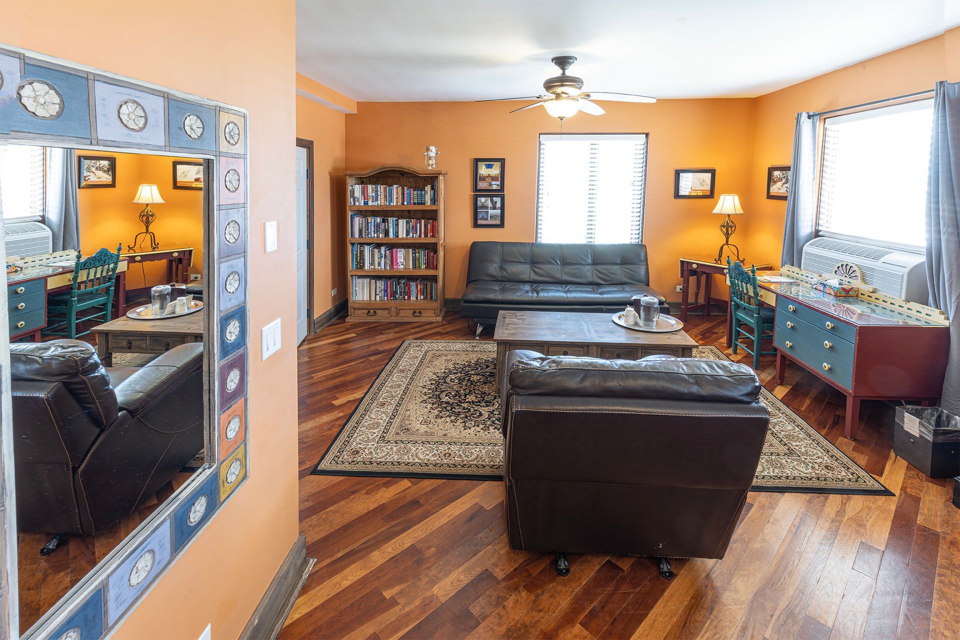 Living room with orange walls, hardwood floors, furniture, and a large mirror.