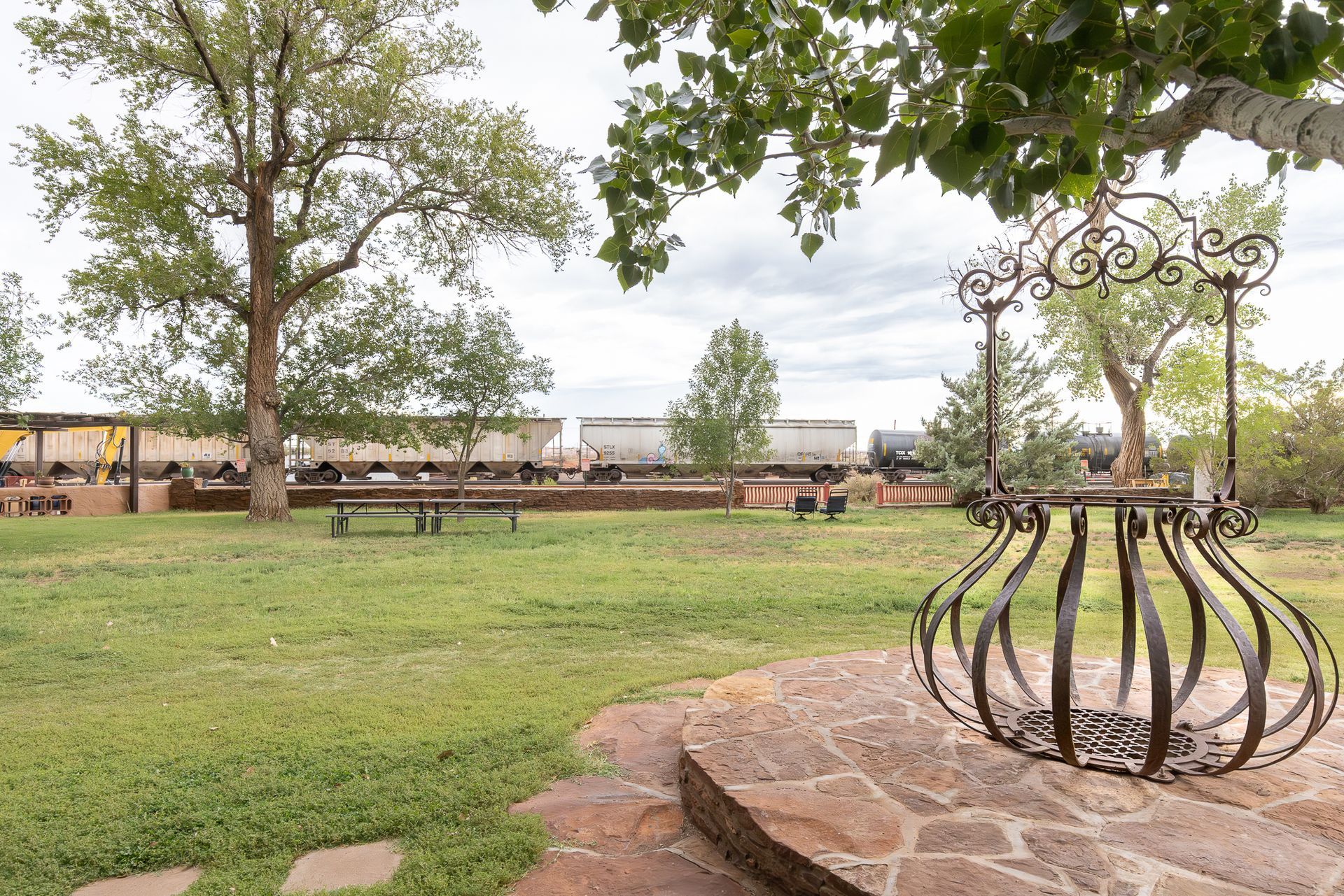 Ornamental well in a grassy yard; train in background.