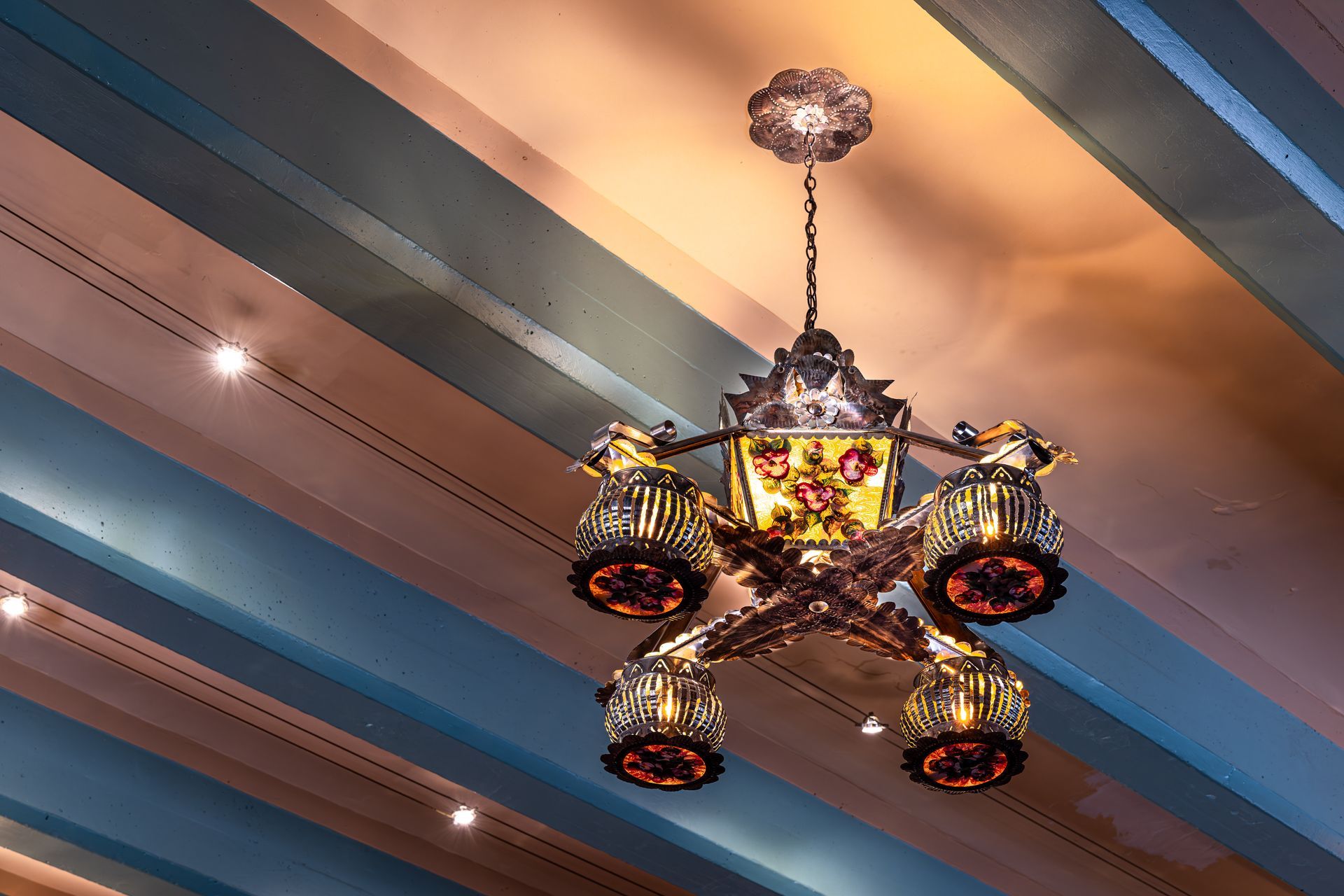 Ornate chandelier hanging from a blue and tan striped ceiling.