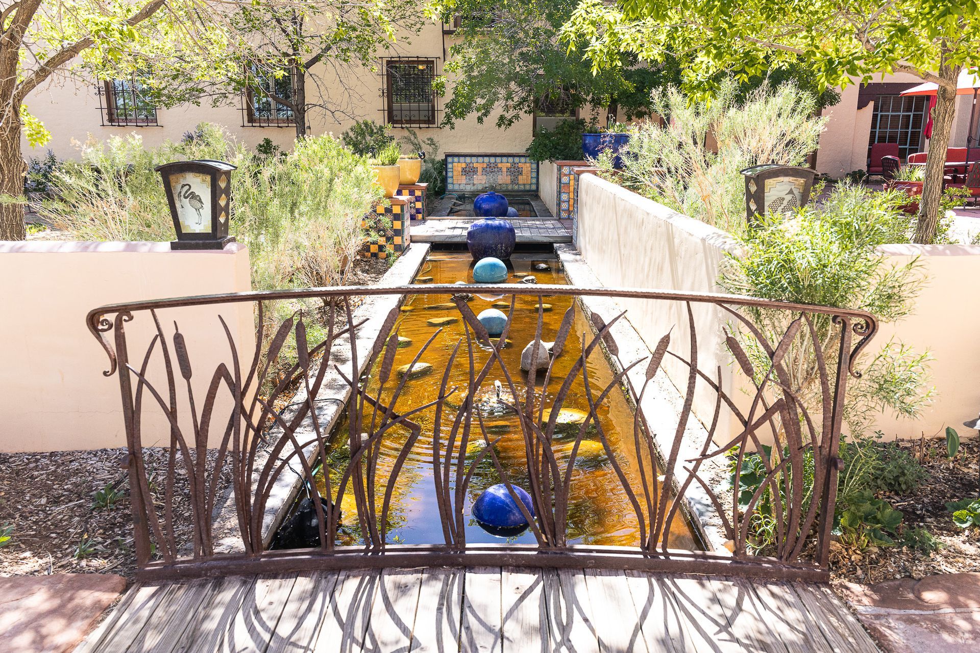 Decorative water feature with bridge, blue spheres, and lush landscaping.