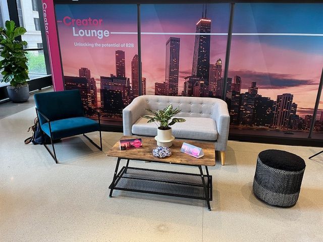 Creator Lounge interior with couch, chair, and coffee table against a city skyline backdrop.