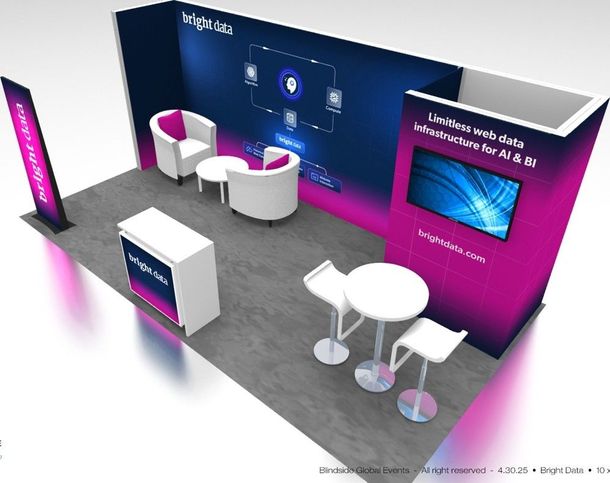 A trade show booth with a seating area and a display screen, in shades of pink and blue.