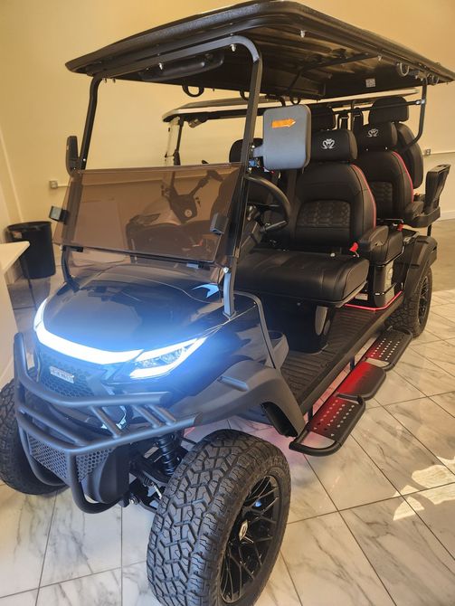 A golf cart is parked on a gravel road next to a lake.