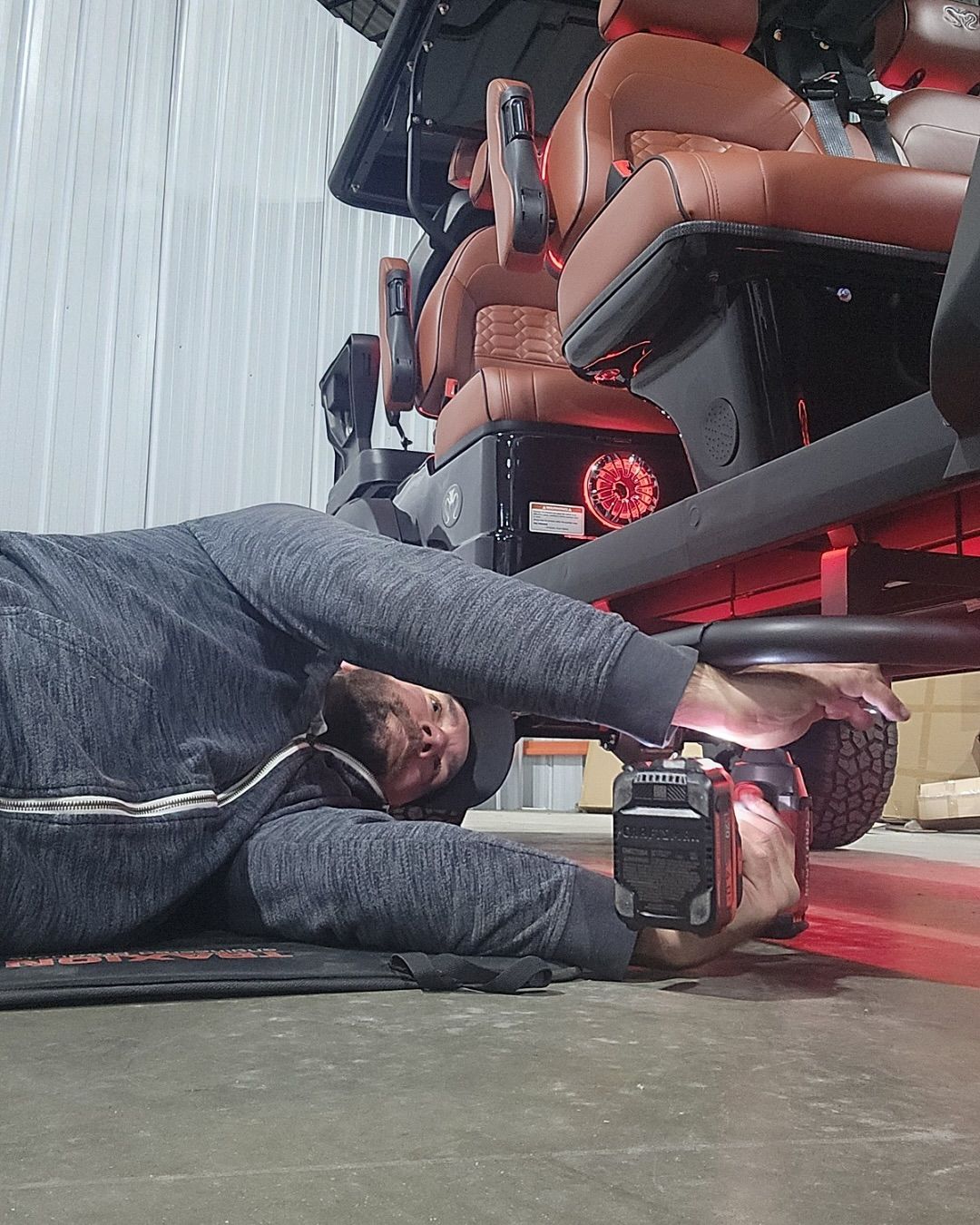 A man is laying on the ground working on a vehicle.