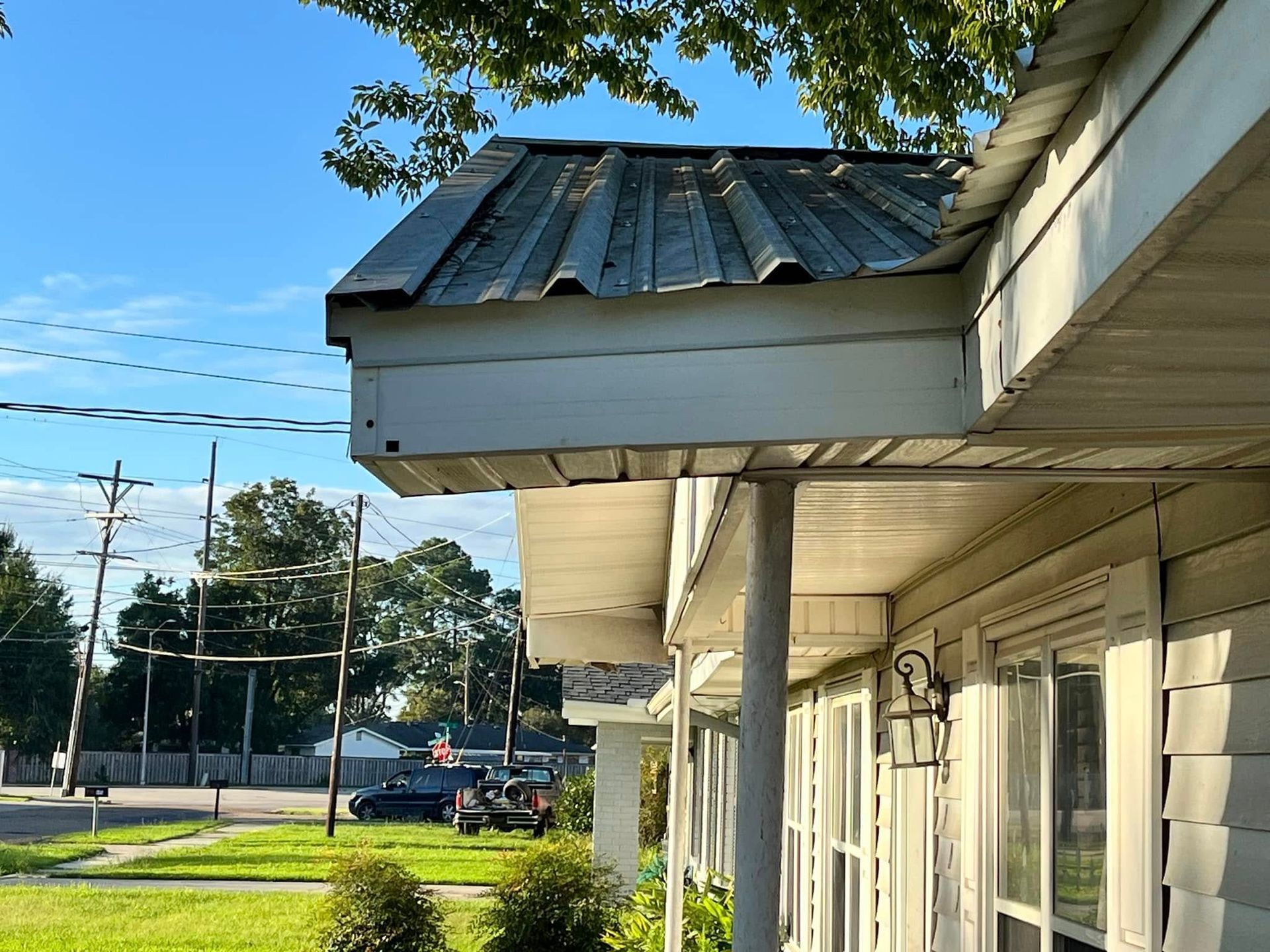 A white house with a metal roof and a porch