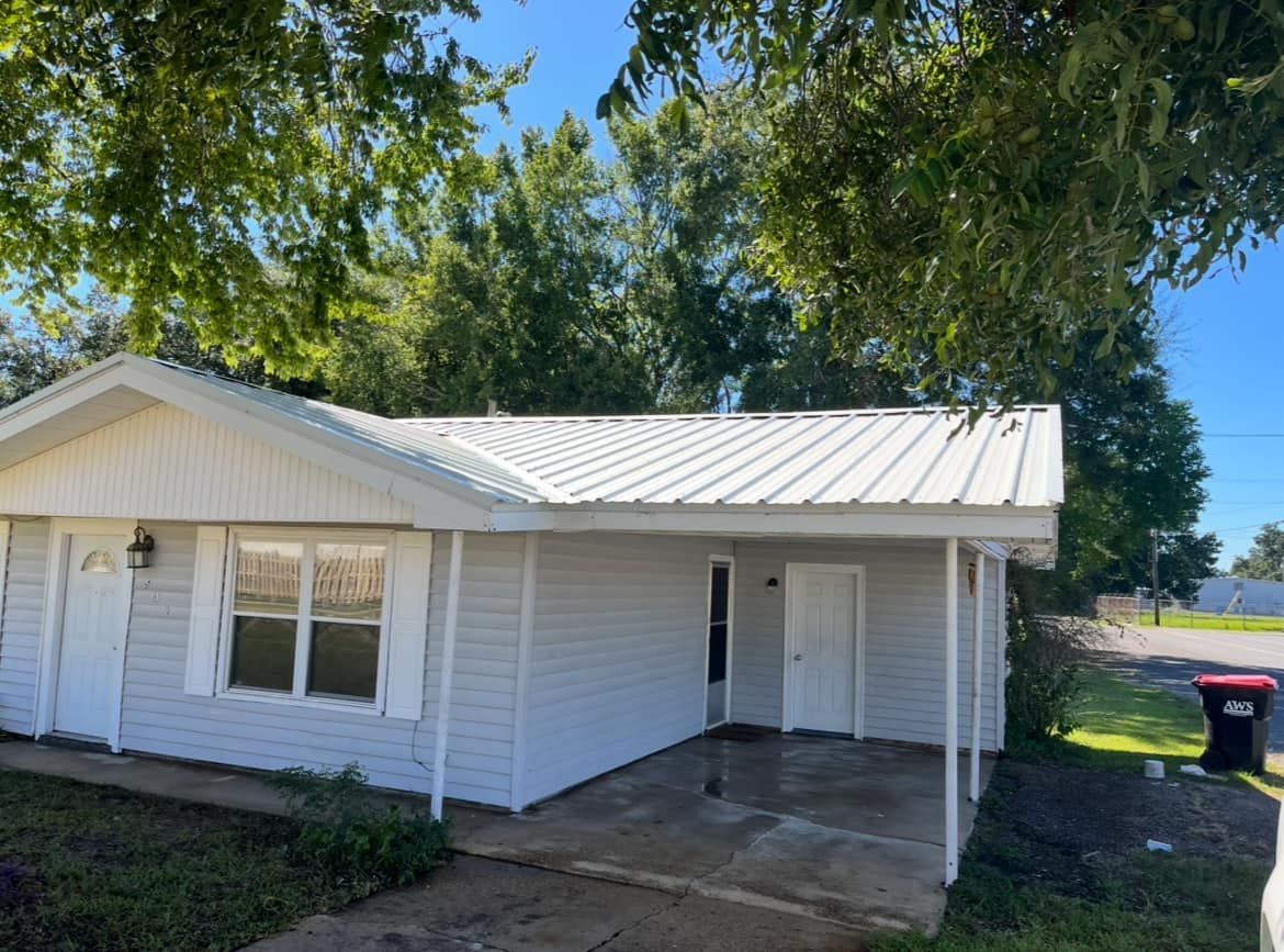 A small white house with a metal roof and a porch.