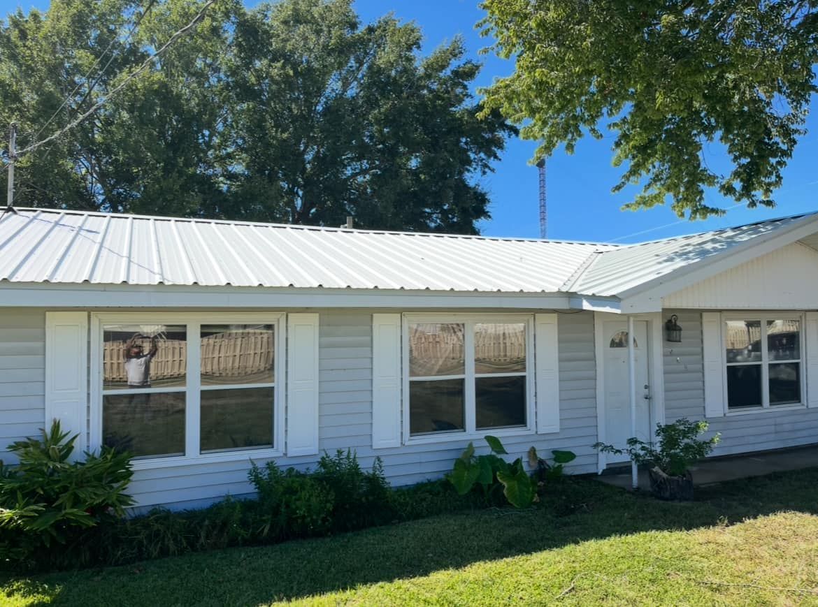 A white house with a metal roof and white shutters
