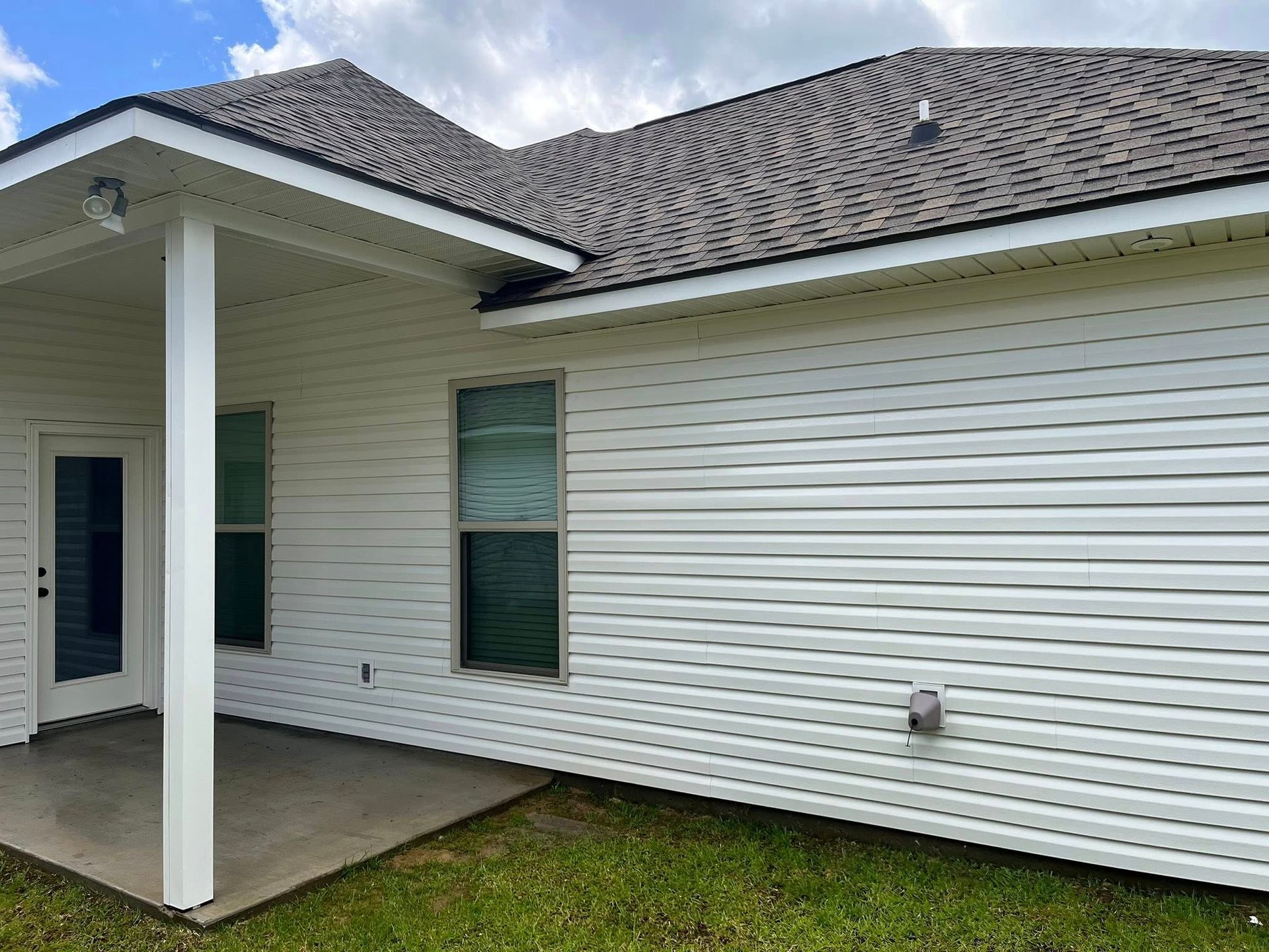 A white house with a covered patio and a gray roof.