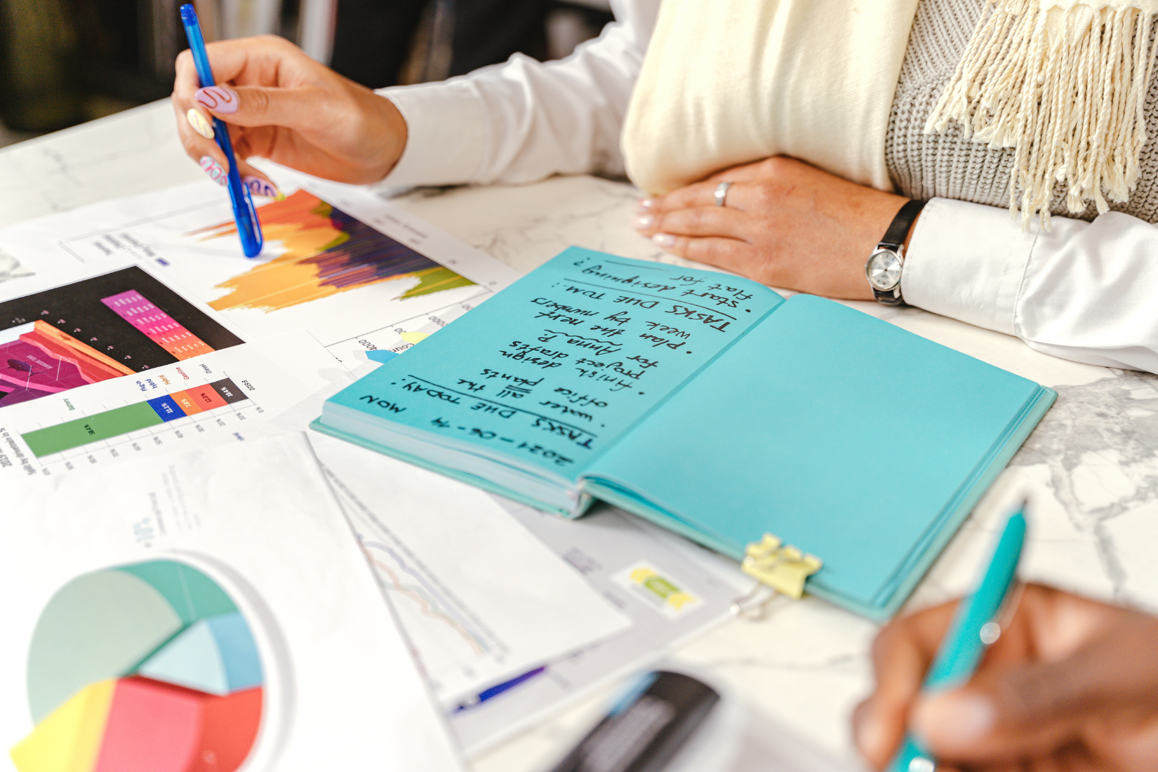 A Virtual Assistant is sitting at a table with a notebook and a pen.