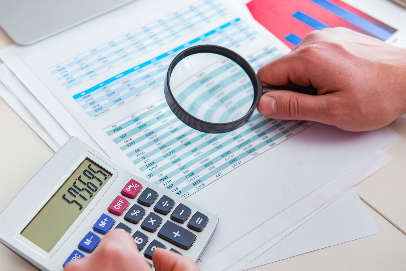 A Virtual Assistant is holding a magnifying glass over a calculator.