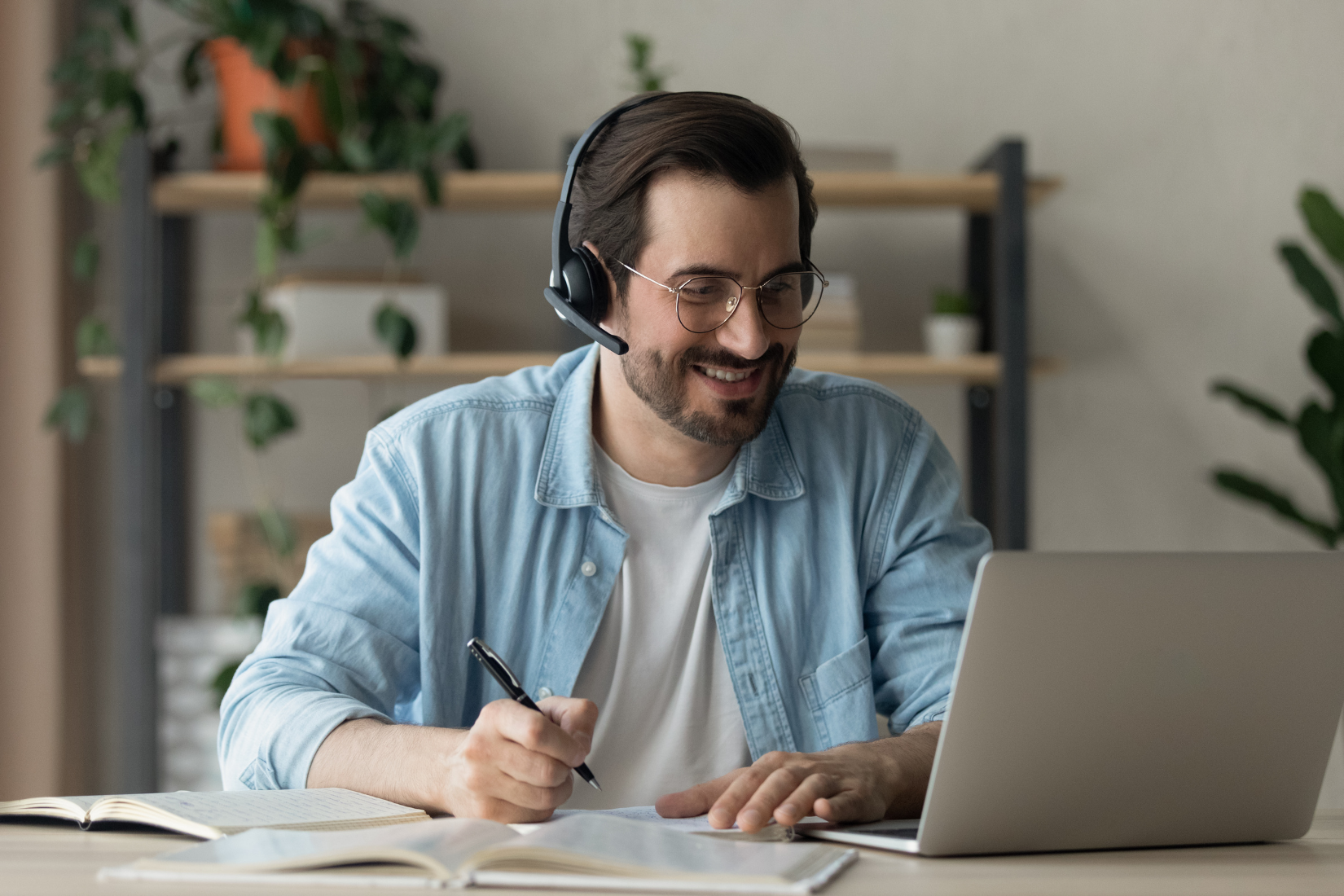 A Virtual Assistant wearing headphones is sitting at a desk using a laptop computer.