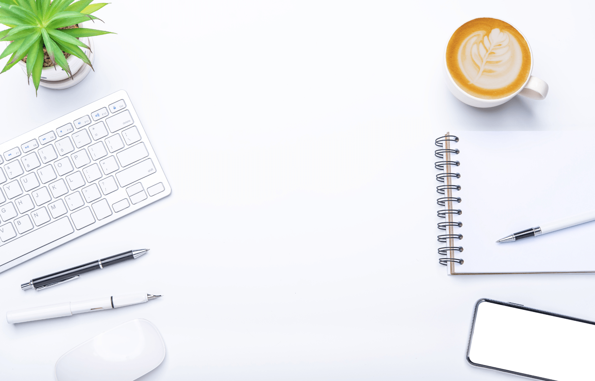 A white desk with a keyboard , mouse , notebook , pen , and a cup of coffee.