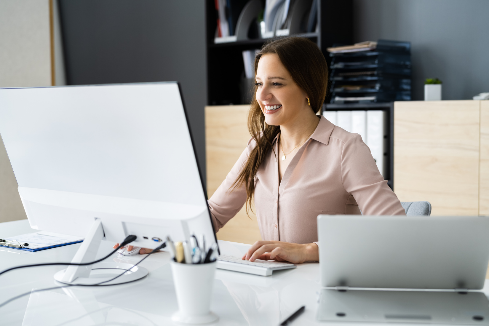 A Virtual Assistant is sitting at a desk in front of a computer.